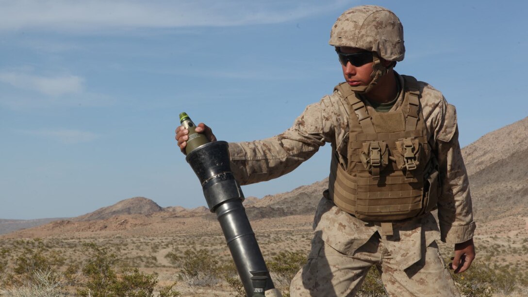 Pfc. Michael Ainsworth, a mortarman with Weapons Company, 3rd Battalion, 5th Marine Regiment, prepares to drop a mortar round during a combined-arms raid at Army National Training Center Fort Irwin, California April 11, 2015. The raid was conducted by 1st Light Armored Reconnaissance Battalion as part of exercise Desert Scimitar 2015.