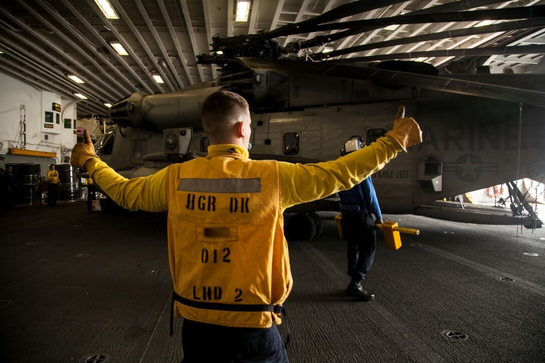 A U.S. Navy Sailor with the Essex Amphibious Ready Group guides a CH-53E Sea Stallion into the hangar bay of the USS Essex (LHD 2) off the coast of San Diego, May 11, 2015. The Marines and Sailors of the 15th Marine Expeditionary Unit and ESSEX ARG were departing for a seven-month deployment. (U.S. Marine Corps photo by Cpl. Elize McKelvey/Released)