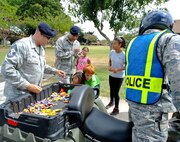 647th Security Forces Squadron Defenders stop to hand out candy during their Police on Patrol Parade through Hickam Communities to kick off Police Week May 11, 2015, at Joint Base Pearl Harbor-Hickam, Hawaii. In 1962 President Kennedy declared May 15 as National Peace Officers’ Memorial Day and the calendar week in which May 15 falls as National Police Week. Since then, Police Week has served as a time to pay special recognition to law enforcement officers who lost their lives in the line of duty for the safety and protection of others. (U.S. Air Force photo by Tech. Sgt. Terri Paden)