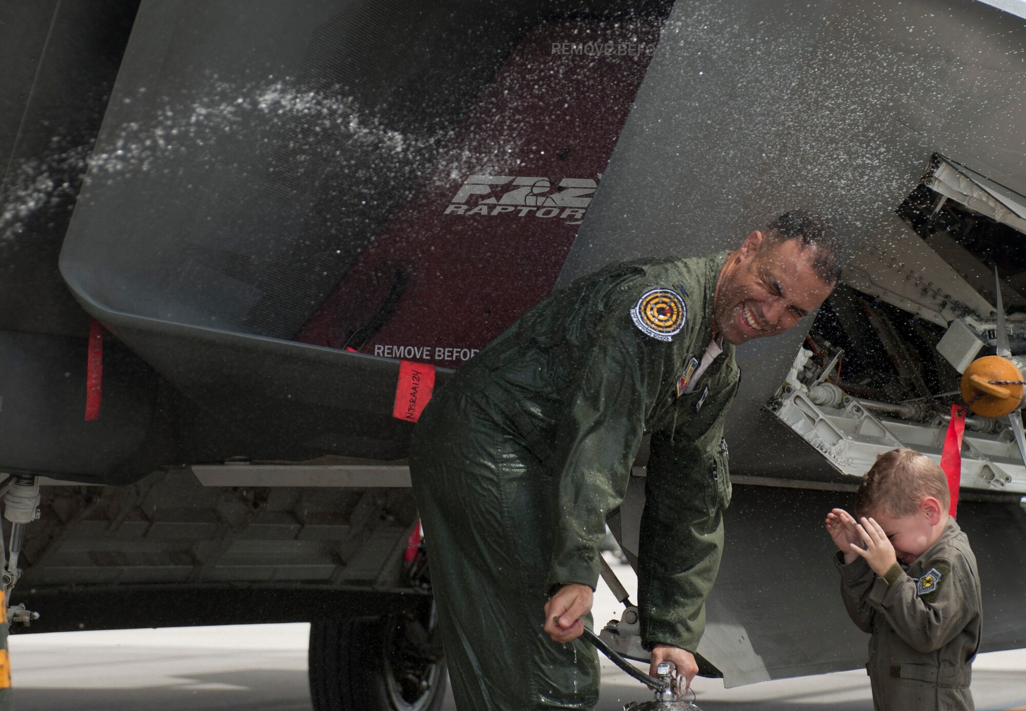 Col. Adrian Spain, U.S. Air Force Weapons School commandant, laughs with his son while being hosed down after his final flight as the USAFWS commandant at Nellis Air Force Base, Nev., May 11, 2015. Spain, who has served at Nellis AFB since June 2013, will take over as commander of the 53rd Wing at Eglin AFB, Fla. (U.S. Air Force photo by Airman 1st Class Mikaley Towle)