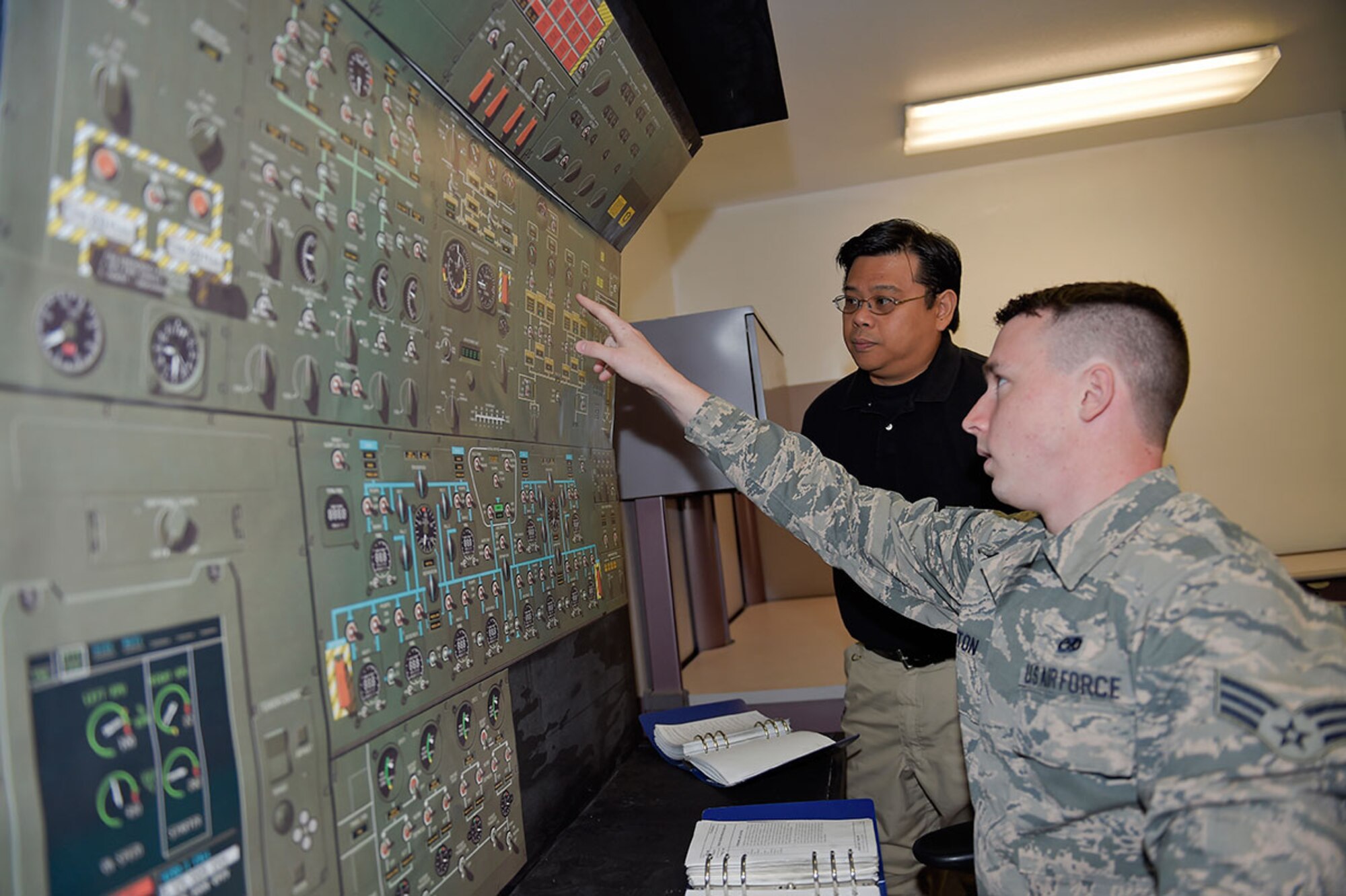 Jolly Tangog, an equipment specialist with Air Force engineering and technical services for the 732nd Air Mobility Squadron, supervises Senior Airman Adam Orton, a jets lead technician, as he uses a C-5M Super Galaxy maintenance trainer on Joint Base Elmendorf-Richardson, Alaska, May 7, 2015. Tangog came up with the cost-saving idea to build a trainer at JBER rather than sending Airmen away on a temporary duty for expensive refresher training. (U.S. Air Force photo/Alejandro Pena)