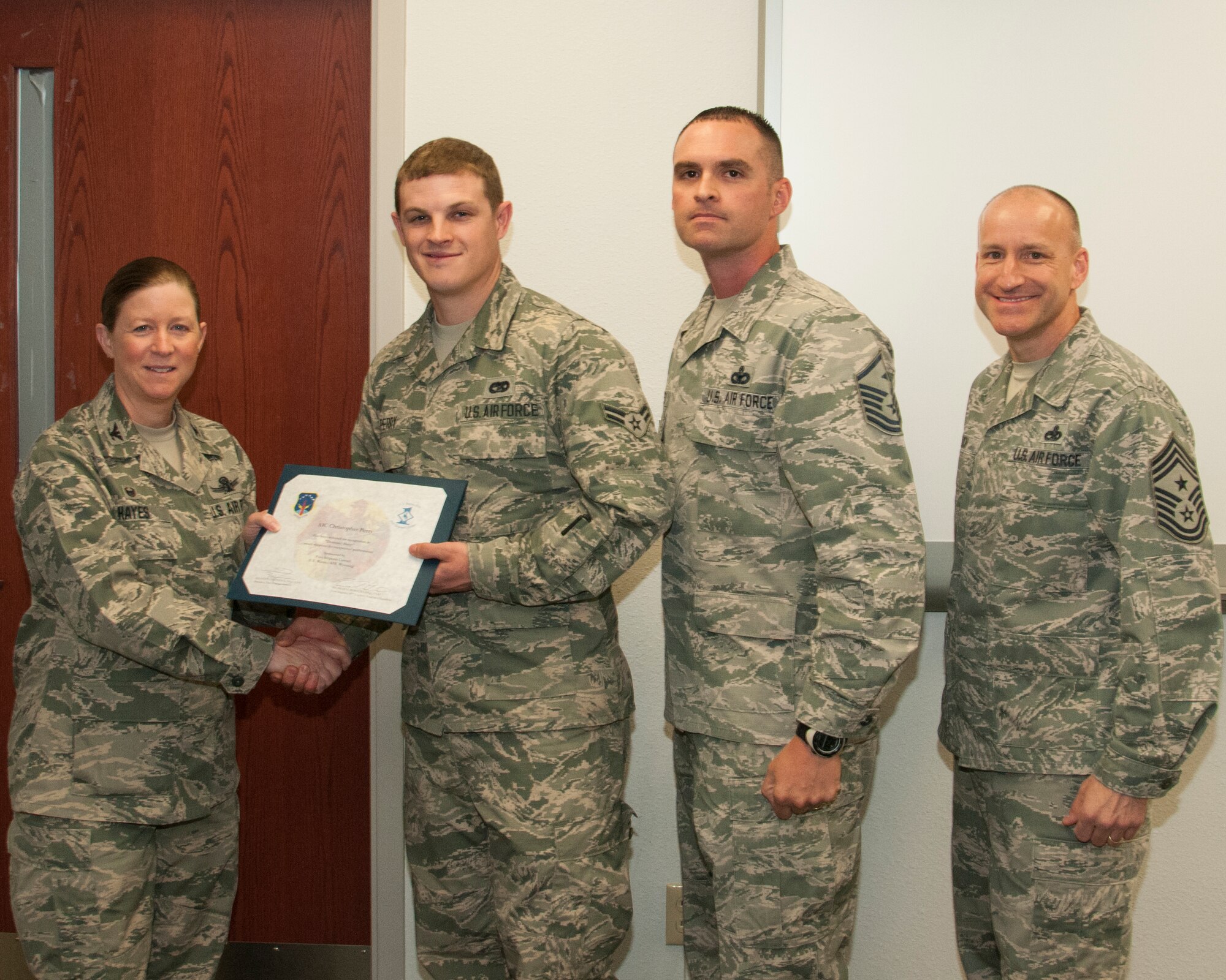 Airman 1st Class Christopher Perry, 90th Logistics Readiness Squadron vehicles and vehicle maintenance technician, poses with Col. Tracey Hayes, 90th Missile Wing commander; Master Sgt. Ricardo Borecki, 90th Logistics Readiness Squadron first sergeant; and Chief Master Sgt. Samuel Couch, 90th MW command chief, during the wing's first sergeants' Diamond Sharp Award presentation May 12, 2015, on F.E. Warren Air Force Base, Wyo. First sergeants nominate an Airman in their respective squadrons for the award, and the first sergeants select the three top contenders for the award each month. (U.S. Air Force photo by Senior Airman Jason Wiese)