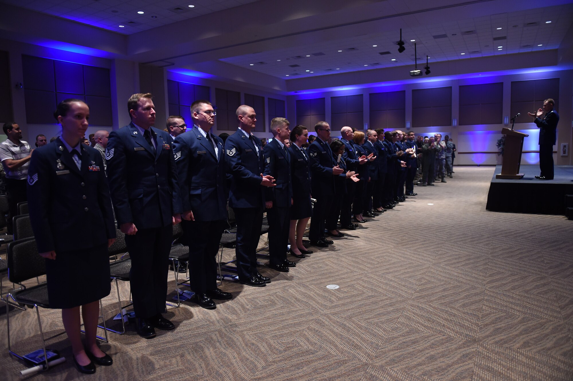 Team Buckley members stand during the Community College of the Air Force graduation ceremony May 12, 2015, at the Leadership Development Center on Buckley Air Force Base, Colo. Graduates received various Associates in Applied Sciences degrees. CCAF is the only degree-granting institution in the world open exclusively to enlisted members. (U.S. Air Force photo by Airman First Class Samantha Meadors/Released)