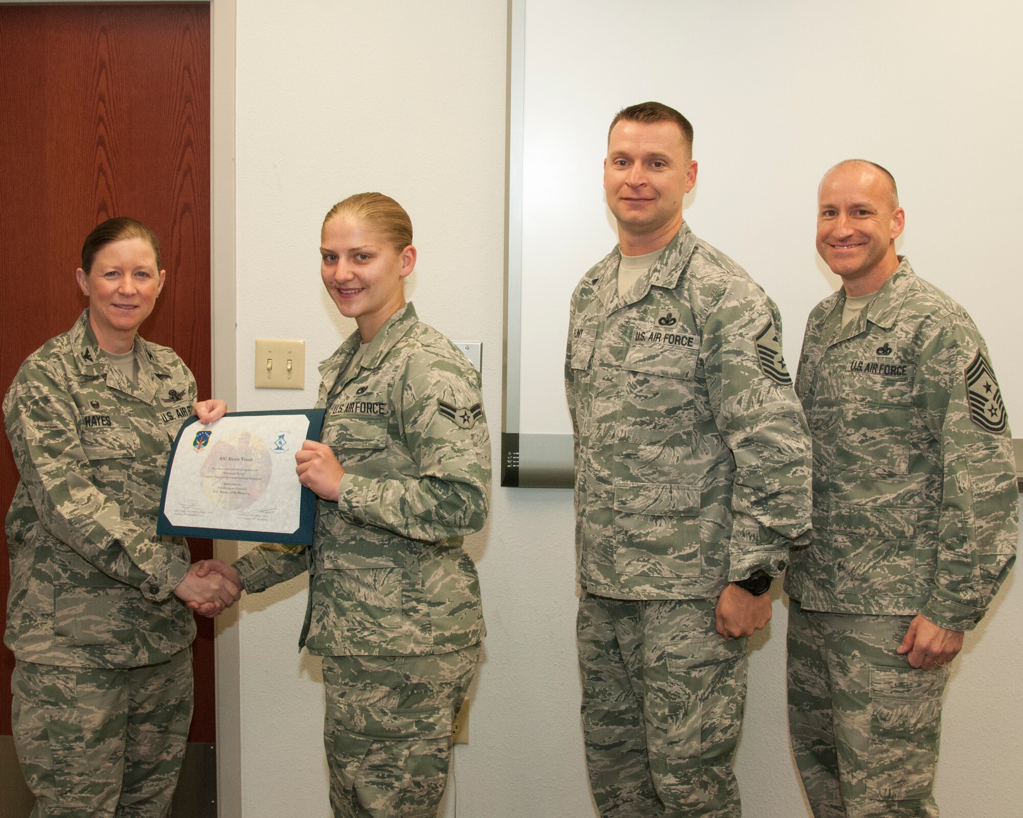 Airman 1st Class Alexis Visser, 90th Munitions Squadron re-entry system/re-entry vehicle team member, poses with Col. Tracey Hayes, 90th Missile Wing commander; Master Sgt. Daniel Flint, 90th Missile Maintenance Squadron and 90th Munitions Squadron first sergeant; and Chief Master Sgt. Samuel Couch, 90th MW command chief, during the wing's first sergeants' Diamond Sharp Award presentation May 12, 2015, on F.E. Warren Air Force Base, Wyo. First sergeants nominate an Airman in their respective squadrons for the award, and the first sergeants select the three top contenders for the award each month. (U.S. Air Force photo by Senior Airman Jason Wiese)