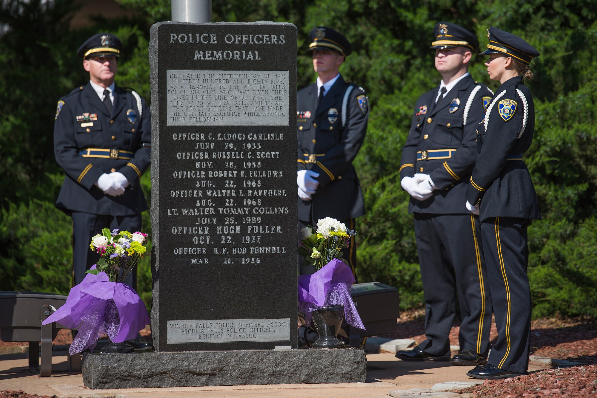 Wichita Falls, Texas, police officers stand around a memorial for officers who have lost their lives in the line of duty at the Wichita Falls police department, May 11, 2015. The local police and sheriff departments of Wichita County honored their sacrifice alongside Sheppard Air Force Base, security police, during their opening ceremony. (U.S. Air Force photo by Senior Airman Kyle Gese/Released)