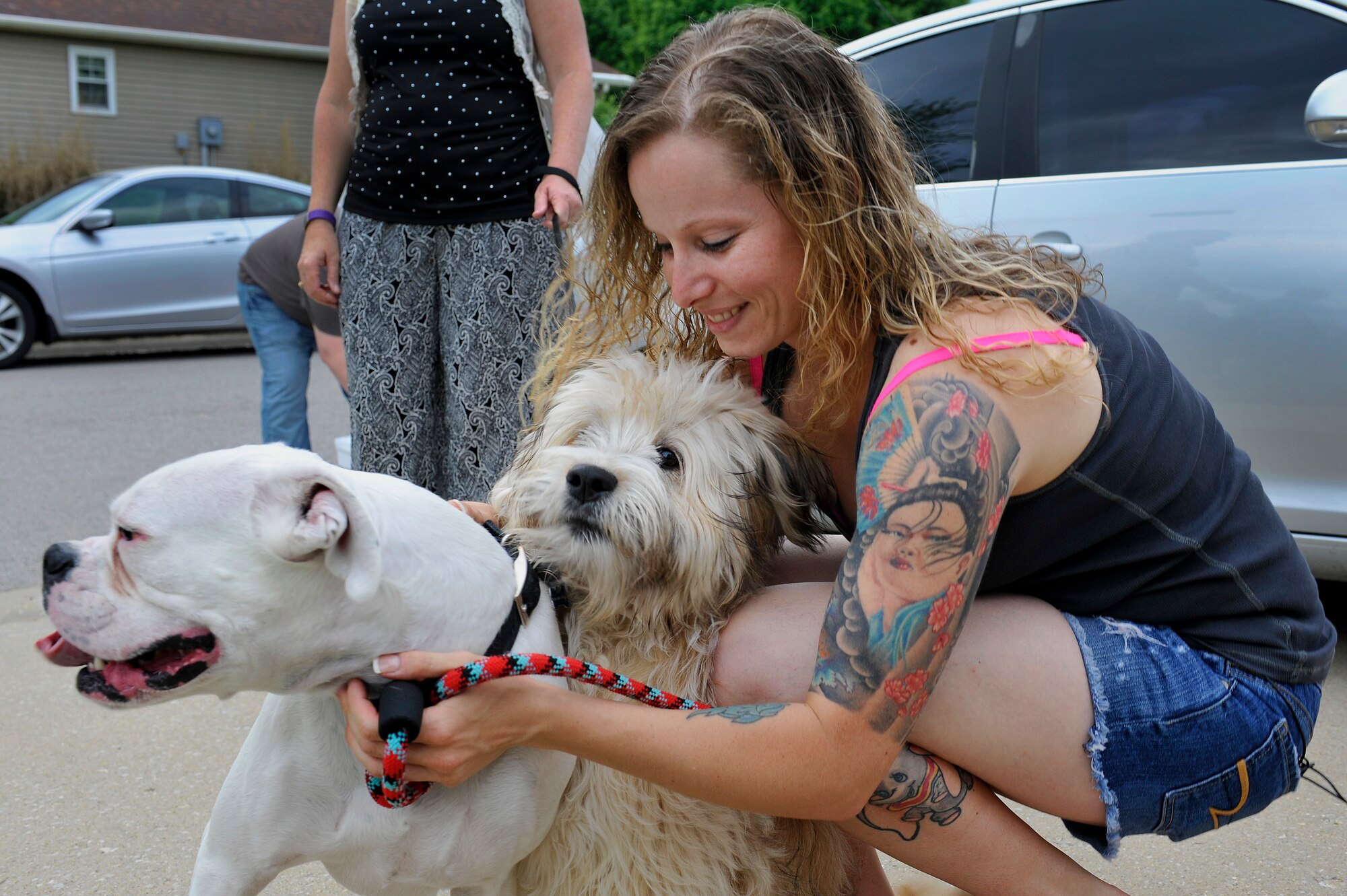 Staff Sgt. Arin Vickers, 435 Supply Chain Operations Squadron, hug Baxter and Bandit, her newly united family, Belleville, Illinois, May 6, 2015. Vickers was gone on a deployment for 6 months and rescued a puppy named Bandit  who she was able to adopt and waited until her deployment was up to be reunited. (U.S. Air Force photo by Airman 1st Class Erica Crossen)