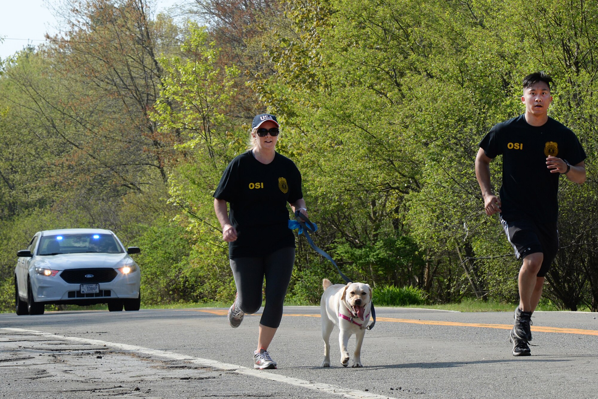 Special Agents Nicole Boucher, running with "Cali," and Darren Canlas, Air Force Office of Special Investigations Detachment 102, participate in the 66th Security Forces Squadron Police Week fun run through Minute Man National Historical Park May 11. On Friday, May 15 at 3:30 p.m., a retreat ceremony will take place at the POW/MIA memorial area on base. This event will feature Lexington Police Chief Mark Corr as the guest speaker. (U.S. Air Force photo by Linda LaBonte Britt)
