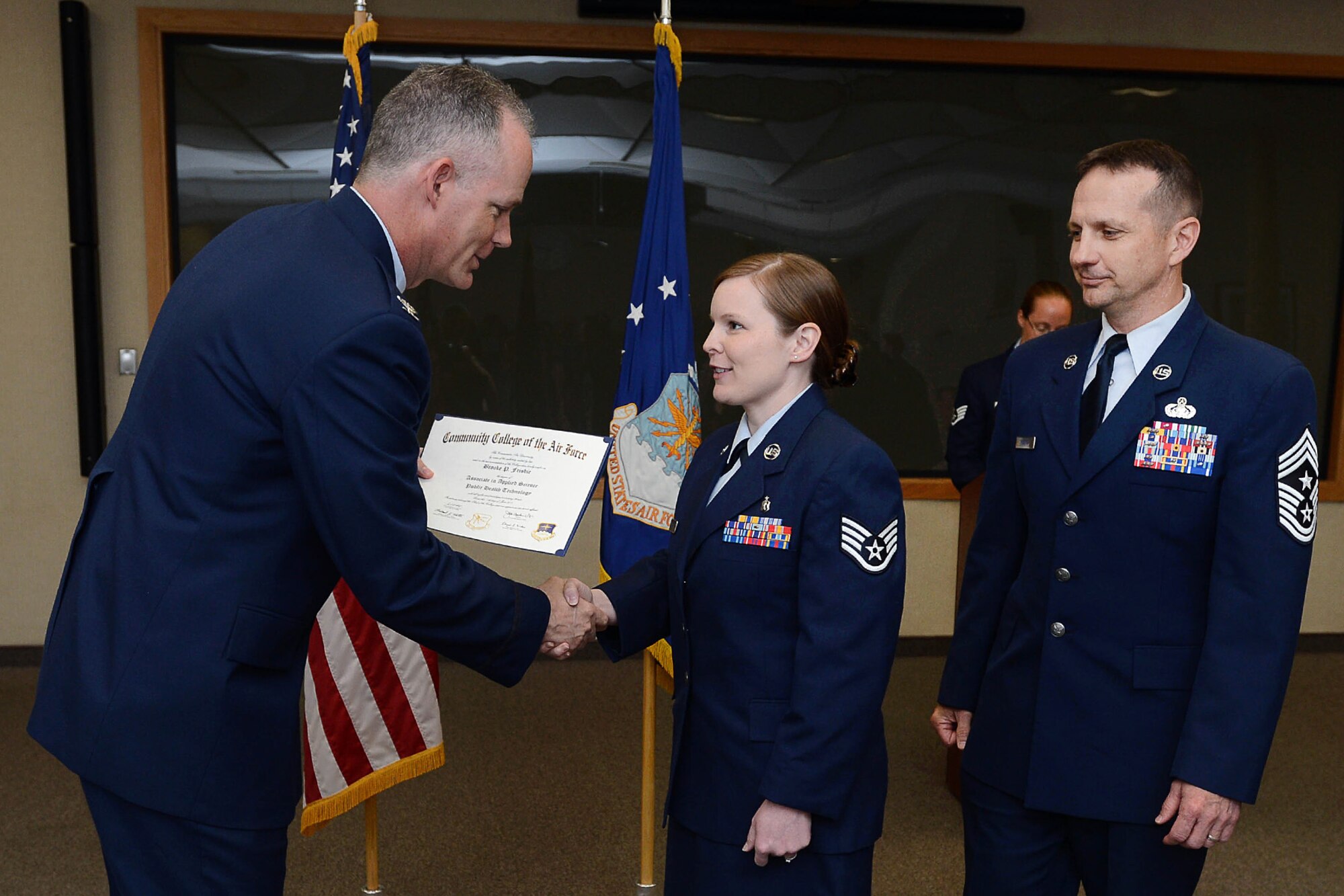 Staff Sgt. Brooke Frisbie (middle) accepts her Community College of the Air Force degree from Col. Michael A. Vogel (left), 66th Air Base Group commander, and Hanscom Command Chief Master Sgt. Craig A. Poling during the CCAF graduation at the Hanscom Conference Center May 8. The CCAF is a federally-chartered degree-granting institution that serves the United States Air Force's enlisted total force. (U.S. Air Force photo by Jerry Saslav)