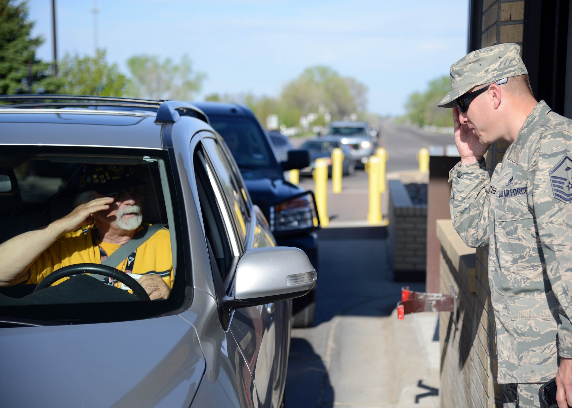 Master Sgt. Jason Whitehead, right, 341st Security Forces Squadron first sergeant, salutes a retiree while checking identification cards at the front gate May 5, 2015, at Malmstrom Air Force Base, Mont. Whitehead enjoys being in the same environment as his Airmen to get a better understanding of their everyday lives. (U.S. Air Force photo/ Airman 1st Class Dillon Johnston)
