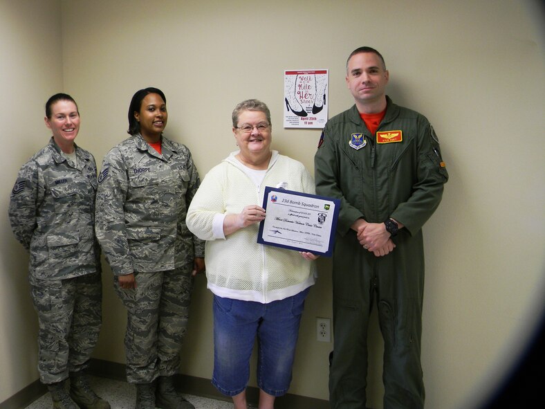 Lt. Col. Kyle Smet, 23rd Bomb Squadron duty commander, Tech. Sgt. Amy Miller, 5th Operational Support Squadron security manager, and Staff Sgt. Candice Thorpe, 23rd Bomb Squadron commander support staff NCO in charge, present Dena Filler, Domestic Violence Crisis Center executive director, with a donation check at the crisis center in downtown Minot, N.D., May 1, 2015. The 5th Operations Group and the 23rd BS raised $523 during a squadron fundraiser for the Walk a Mile in Her Shoes event. (Courtesy photo)