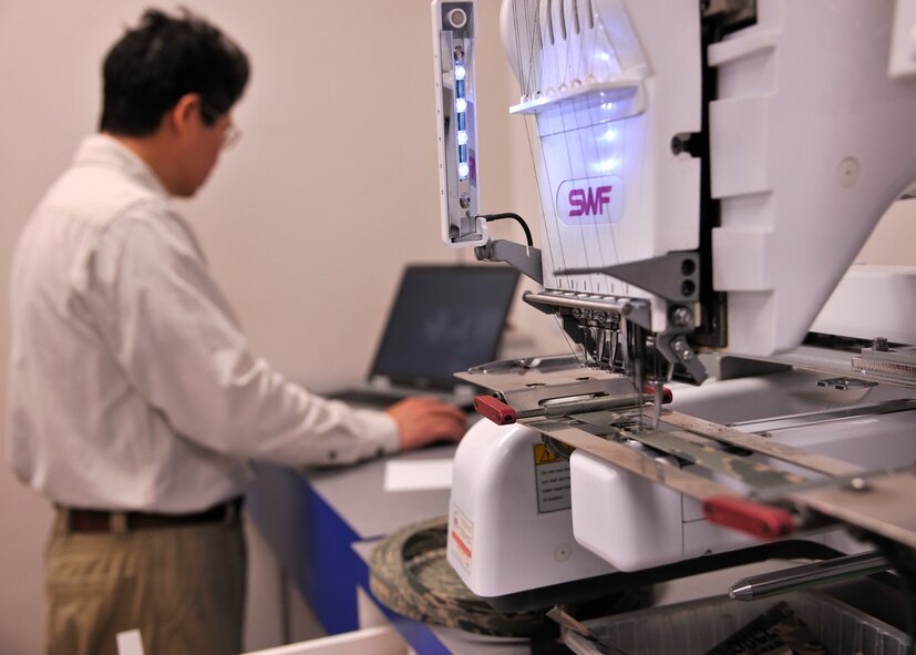 Kin Fat Lai, Exchange alternations manager, uses a computer program in conjunction with an embroidery machine to precisely create patterns on textiles on May 7, 2015, on Grand Forks Air Force Base, N.D. Before coming to America, Lai spent 25 years of his life in Hong Kong where he tailored patterns for clothing factories. (U.S. Air Force photo by Senior Airman Xavier Navarro/released)