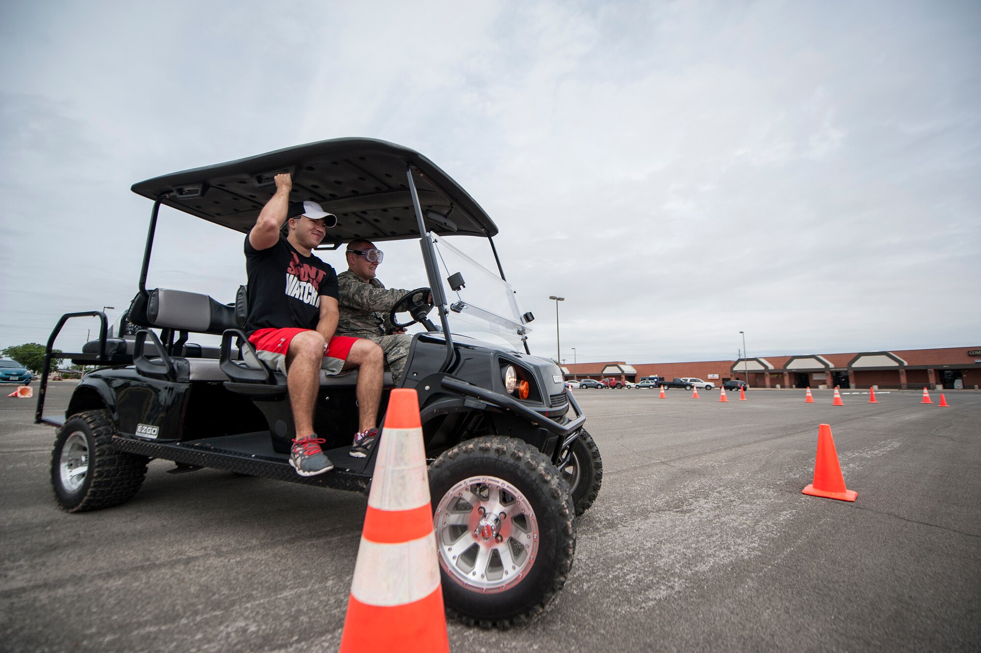 U.S. Air Force 1st Lt. Richard K. Odom, 17th Security Forces Squadron operations officer, drives a golf cart while wearing impairment goggles with Staff Sgt. Tyler D. Wiseman, 17th SFS military working dog handler, at the Drunk Driver Course in front of the commissary Goodfellow Air Force Base, Texas, on May 11, 2015. Driving the golf cart while wearing the goggles allows participants to experience driving under the influence. (U.S. Air Force photo by Senior Airman Michael Smith/Released)