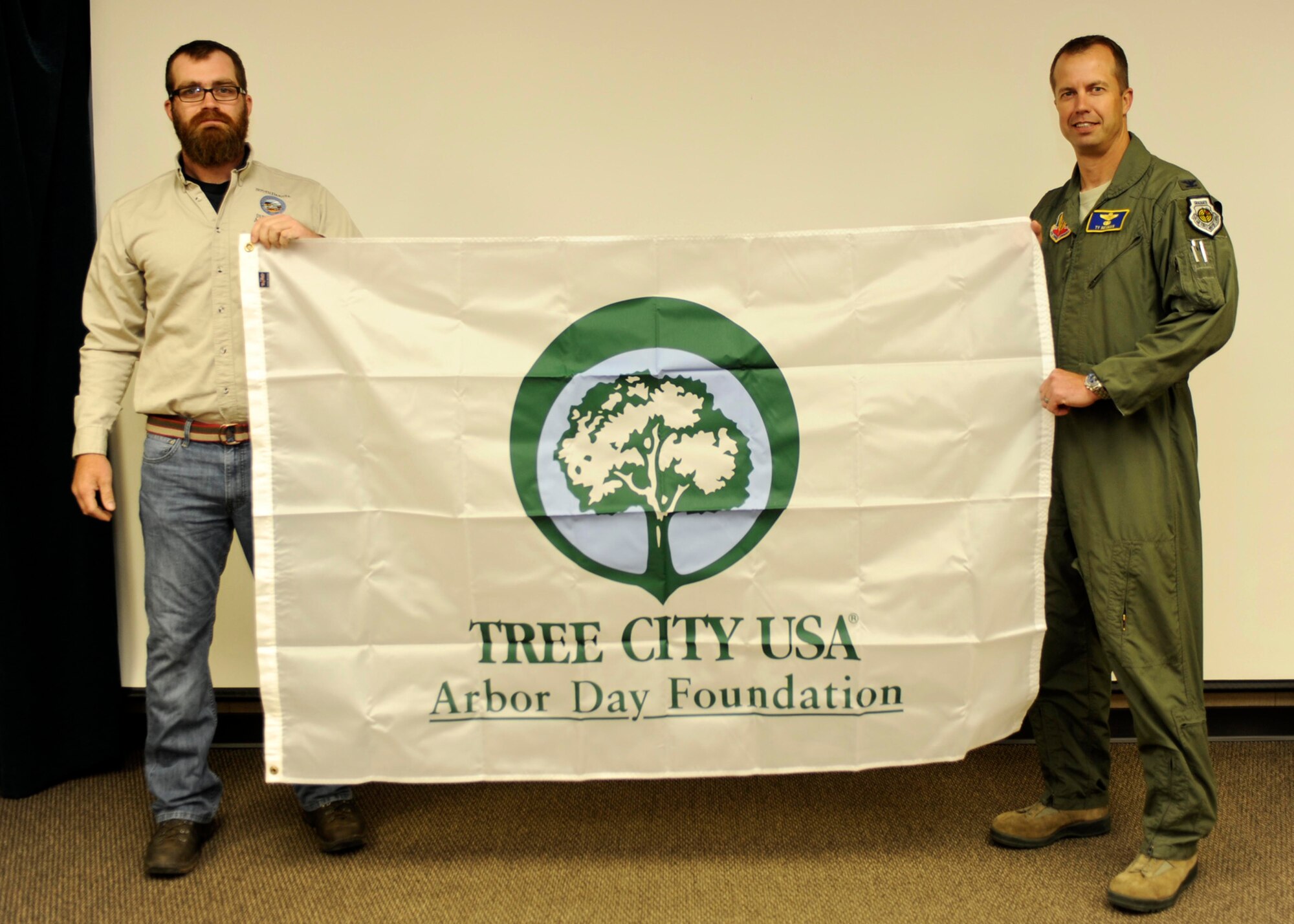 Col. Ty Neuman, 28th Bomb Wing vice commander, accepts an Arbor Day flag from Andy Bernard, South Dakota State forester, recognizing Ellsworth Air Force Base as the 2014 Tree City U.S.A. recipient, during the Environment, Safety and Occupational Health Council meeting on Ellsworth AFB, S.D., May 7, 2015. Ellsworth has been recognized 16 consecutive years for the base’s efforts and commitment to effective urban forest management. (U.S. Air Force photo by Tech. Sgt. Jerry Fleshman)