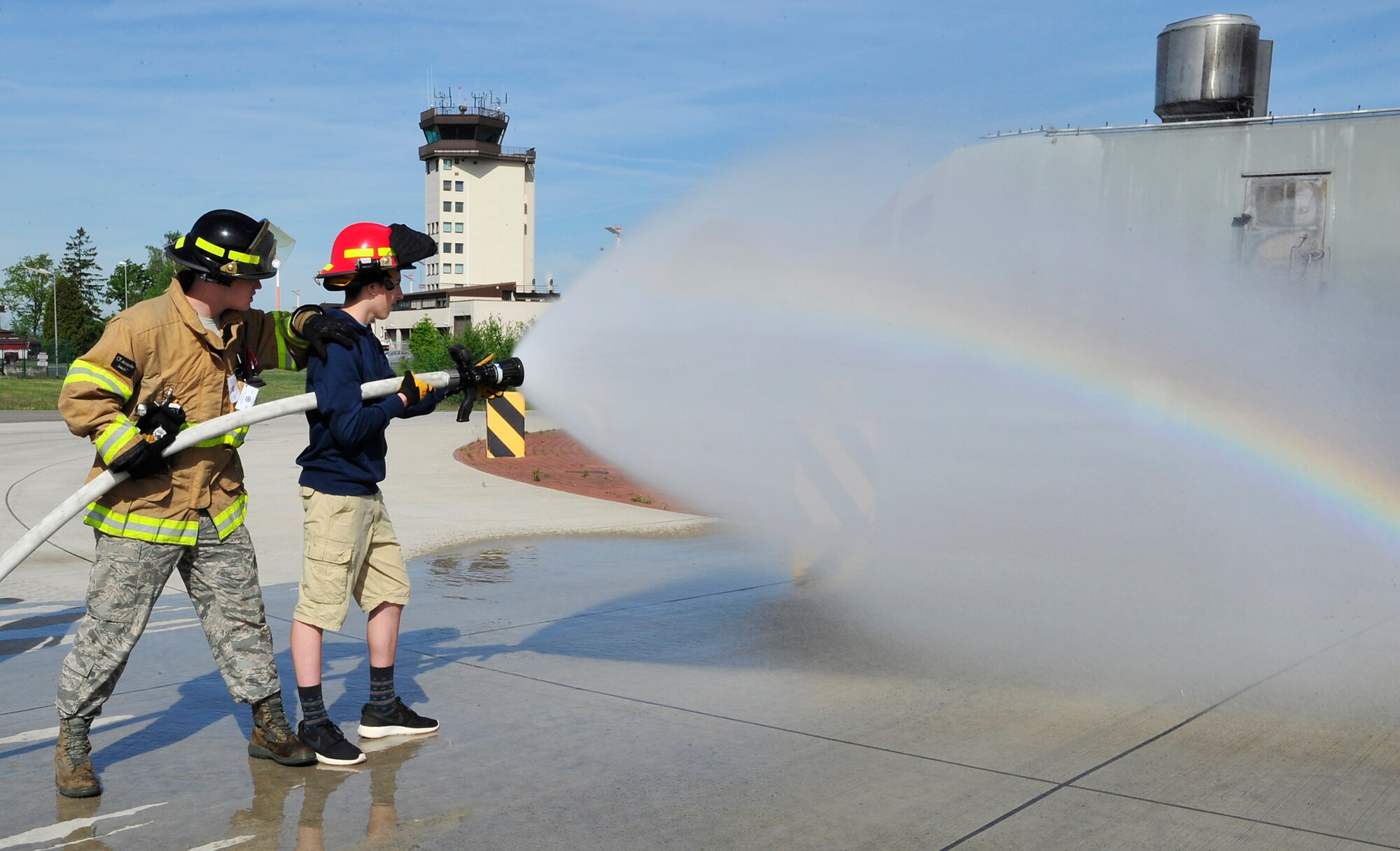 Airman 1st Class Trey Murray, 86th Civil Engineer Squadron firefighter, shows a student how to properly secure and spray a fire hose during Job Shadow Day May 8, 2015, at Ramstein Air Base, Germany. Ramstein Middle and High School students had the opportunity to learn about the different careers the Air Force has to offer by touring facilities and receiving hands-on lessons. (U.S. Air Force photo/Airman 1st Class Larissa Greatwood)