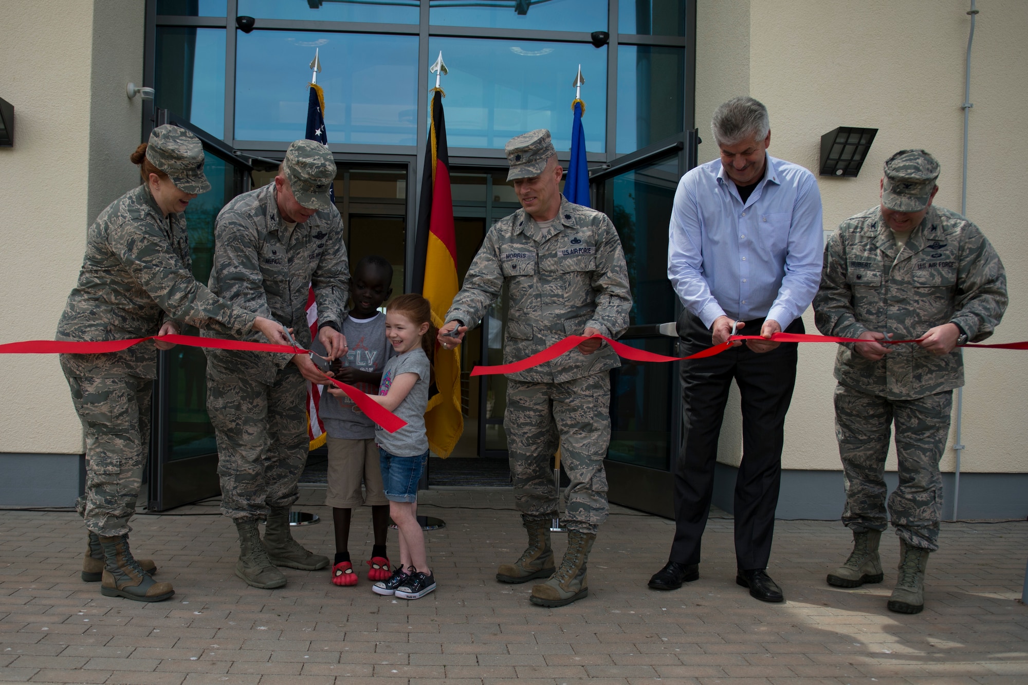 Leadership of the 52nd Fighter Wing and community members perform a ribbon cutting ceremony during the official opening of the new child development center at Spangdahlem Air Base, Germany, May 11, 2015. The new facility can support more than 200 children ages 1-5 and includes a lobby, playground, kitchen and 11 classrooms. (U.S. Air Force photo by Airman 1st Class Luke Kitterman/Released)