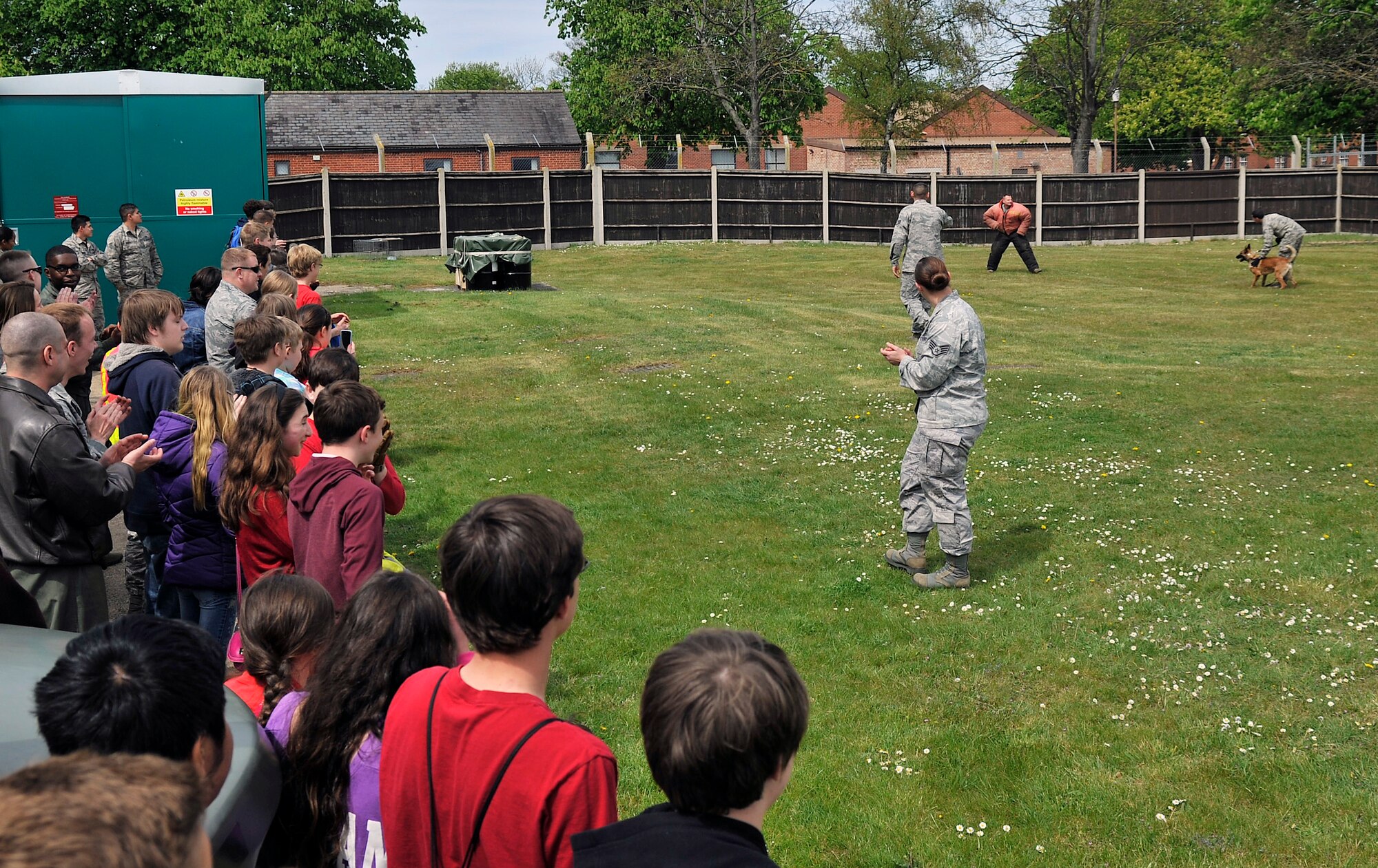 Team Mildenhall children observe a 100th Security Forces Squadron Military Working Dog demonstration during Job Shadow Day May 4, 2015, on RAF Mildenhall, England. Many squadrons on base set up displays and events to give children the opportunity to see different job perspectives. (U.S. Air Force photo by Airman 1st Class Kyla Gifford/Released)