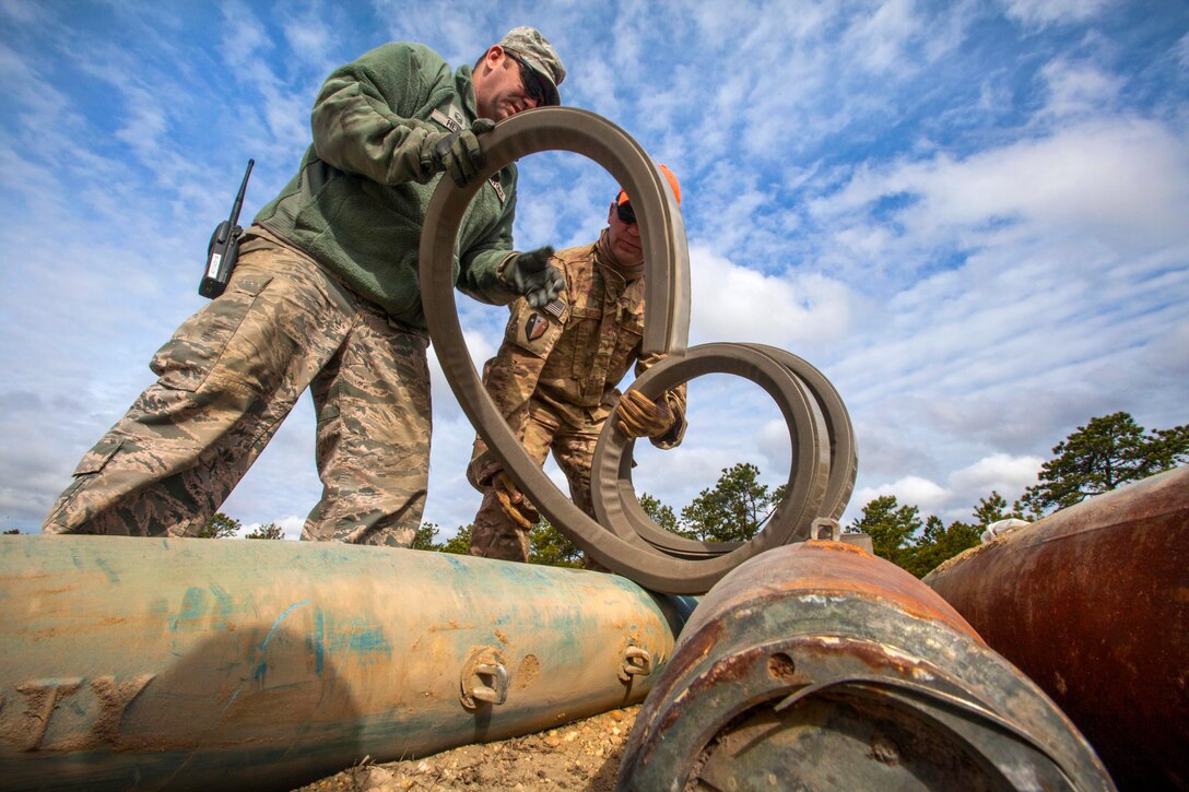 Air Force Reserve Master Sgt. Dustin Heines, left, and New Jersey Air National Guard Staff Sgt. Joe Coates unroll explosive cutting tape during a joint render safe operation at Warren Grove Gunnery Range, Joint Base McGuire-Dix-Lakehurst, N.J., May 1, 2015. Heines is assigned to the 514th Air Mobility Wing Explosive Ordnance Disposal team and Coates is assigned to the 177th Fighter Wing Explosive Ordnance Disposal team.