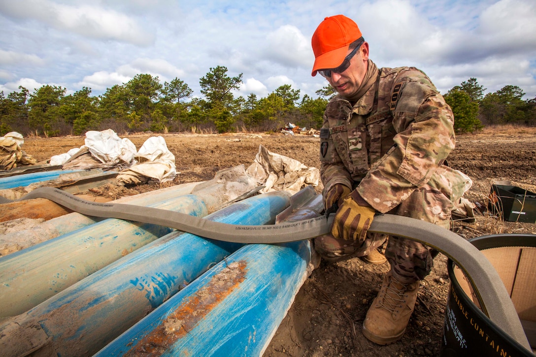 New Jersey Air National Guard Staff Sgt. Joe Coates cuts explosive cutting tape during a joint render safe operation at Warren Grove Gunnery Range, Joint Base McGuire-Dix-Lakehurst, N.J., May 1, 2015. Coates is assigned to the 177th Fighter Wing Explosive Ordnance Disposal team.
