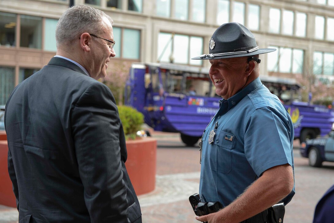 Deputy Defense Secretary Bob Work jokes with a Massachusetts state trooper after a motorcade, May 11, 2015. 