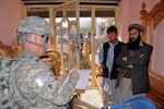 U.S. Army Sgt. Maj. Daniel Collins of Kellogg, Iowa, contracting non-commissioned officer in charge for the Iowa National Guard's 734th Agribusiness Development Team, talks with a furniture store owner and his son in Asadabad, the provincial capital of Afghanistan's Kunar province, Dec. 2.