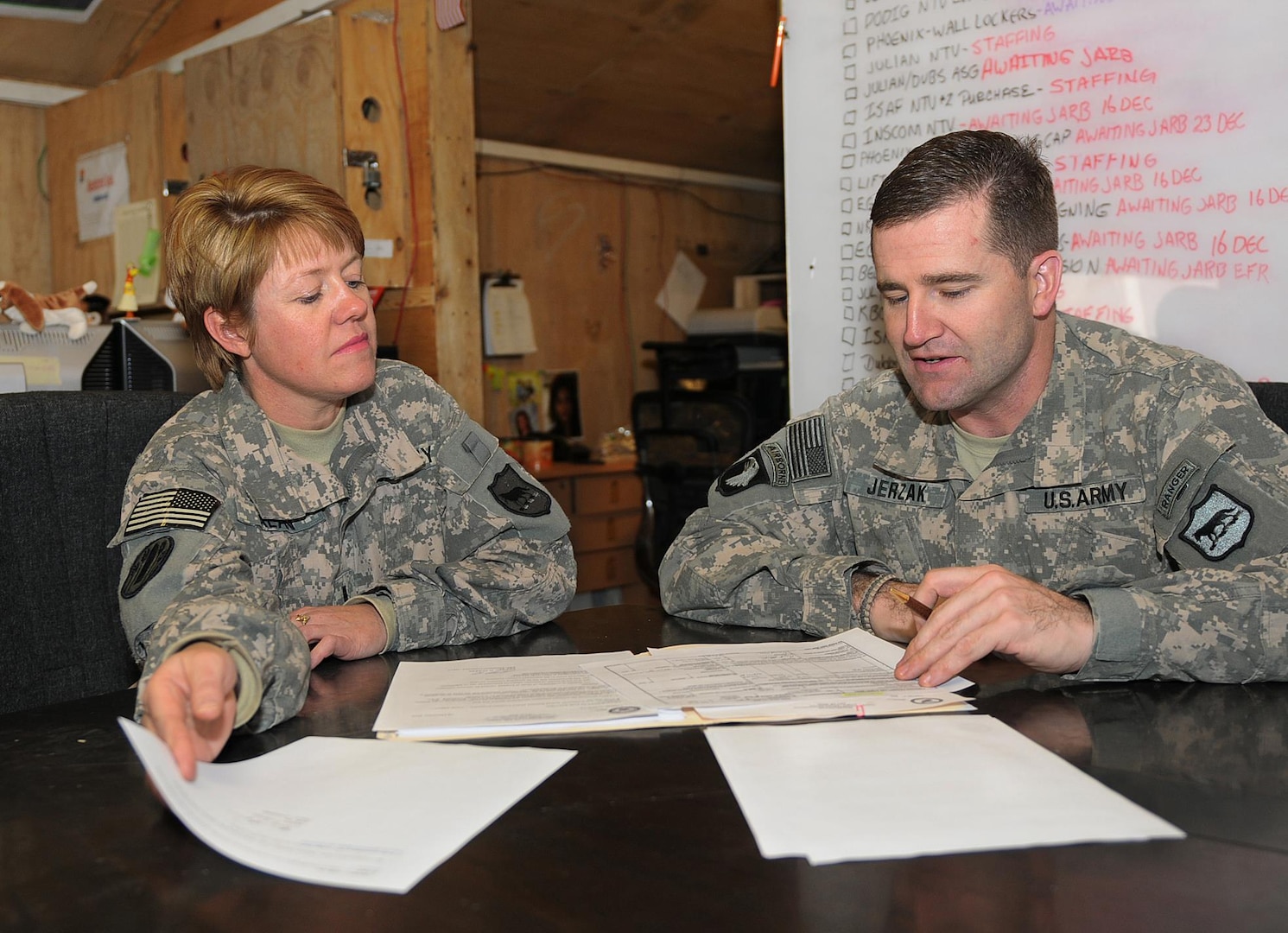 Army Maj. Pete Jerzak, right, director of the Directorate of Resource Management of the 196th Maneuver Enhancement Brigade, South Dakota Army National Guard, visits with Army Chief Warrant Officer 4 Carstin Alan, deputy director for DRM, on a contract Dec. 16, 2010, at Camp Phoenix in Kabul, Afghanistan. Jerzak, of Rapid City, S.D., and Alan, of Whitewood, S.D., work to ensure servicemembers in the Kabul Base Cluster have what they need to be successful in their mission by providing the funding to award and sustain contracts for services and equipment.