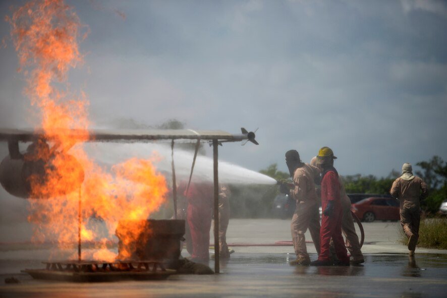 A U.S. Navy shipboard firefighting instructor instructs U.S. Marines from the 31st Marine Expeditionary Wing on Marine Corps Air Station Futenma, Japan, as they battle a simulated aircraft fire on Kadena Air Base, Japan, May 8, 2015. This is the first time the Air Force facility has been used to train members of the Navy and Marines, but the equipment has been used countless times throughout the years to train Air Force firefighters and local community firefighters. (U.S. Air Force photo by Staff Sgt. Maeson L. Elleman)