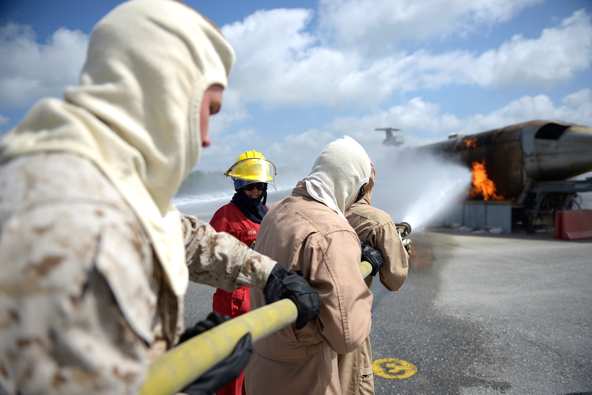 A U.S. Navy shipboard firefighting instructor instructs U.S. Marines from the 31st Marine Expeditionary Wing on Marine Corps Air Station Futenma, Japan, on the proper use of a fire hose to douse a fire at an aircraft fire simulator on Kadena Air Base, Japan, May 8, 2015. Without the use of the 18th Civil Engineer Squadron’s firefighter training area, the Marines would have to travel to another base in the region to maintain their proficiency. (U.S. Air Force photo by Staff Sgt. Maeson L. Elleman)