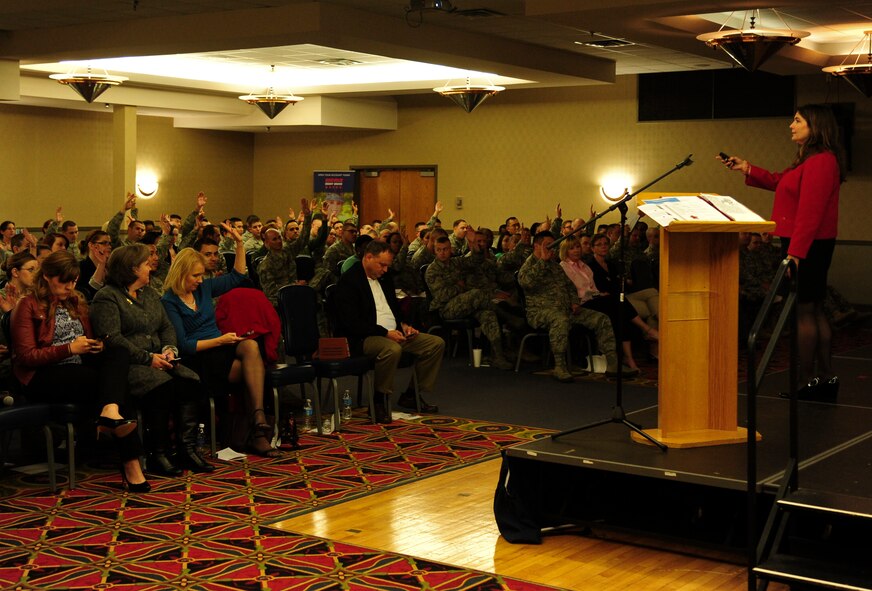 Grand Forks Air Force Base Airmen raise their hands in response to a question from Ellie Kay, consumer finance consultant and best-selling author, May, 12 2015 at the Northern Lights Club on Grand Forks AFB. Kay and her team put on financial education events for military members. Grand Forks AFB was one of six bases to receive the Heroes at Home event. (U.S. Air Force photo by Airman 1st Class Ryan Sparks/released)