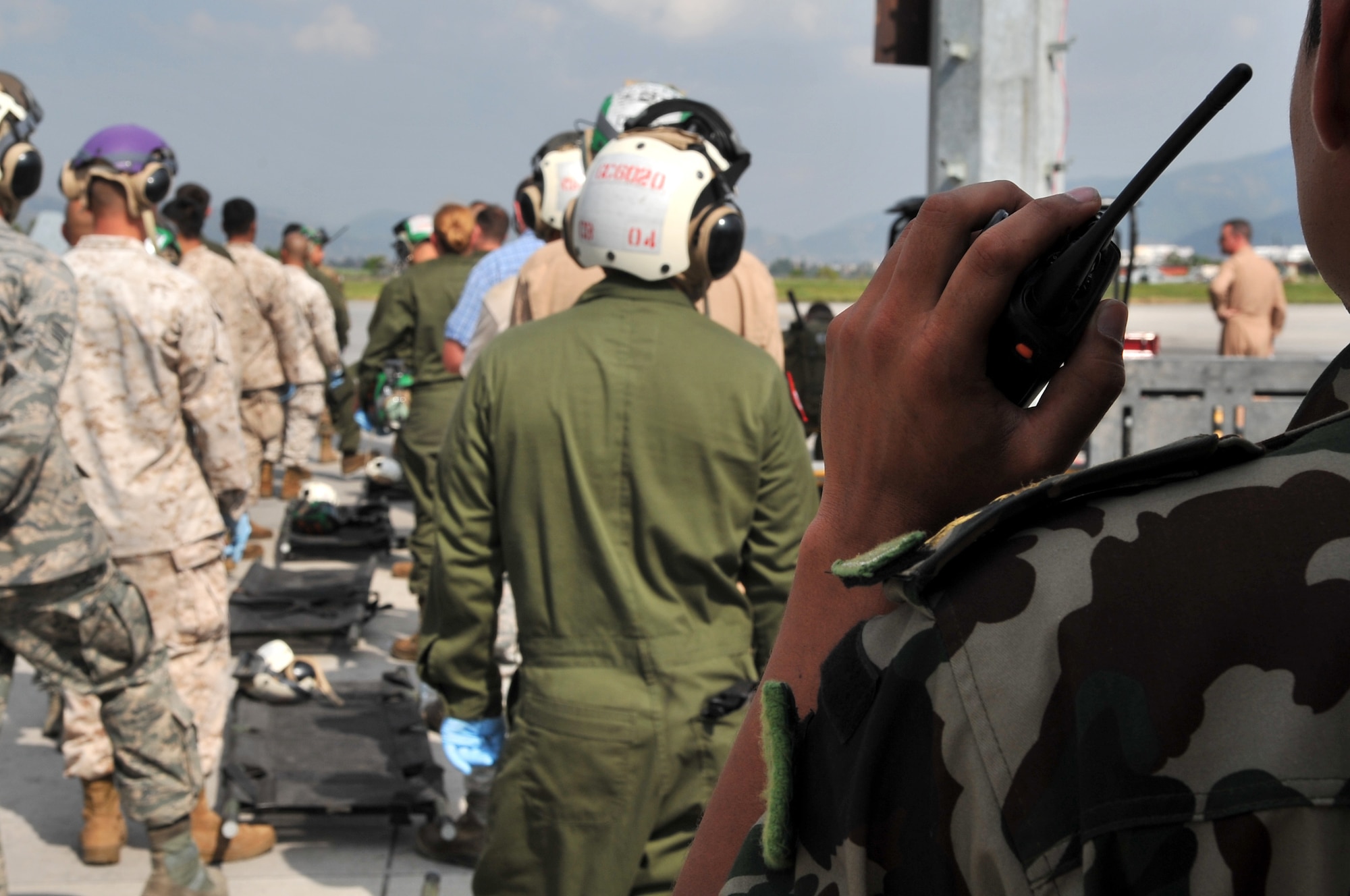 A Nepalese army soldier makes radio contact while U.S. Marines and Airmen standby with litters to transport earthquake victims at the Tribhuvan International Airport in Kathmandu, Nepal, May 12, 2015. Joint Task Force-505 members worked with the Nepalese army to triage, treat and transport patients after a 7.3 magnitude earthquake struck the same day following a 7.8 magnitude earthquake that devastated the nation April 25, 2015. (U.S. Air Force photo by Staff Sgt. Melissa B. White/Released)
