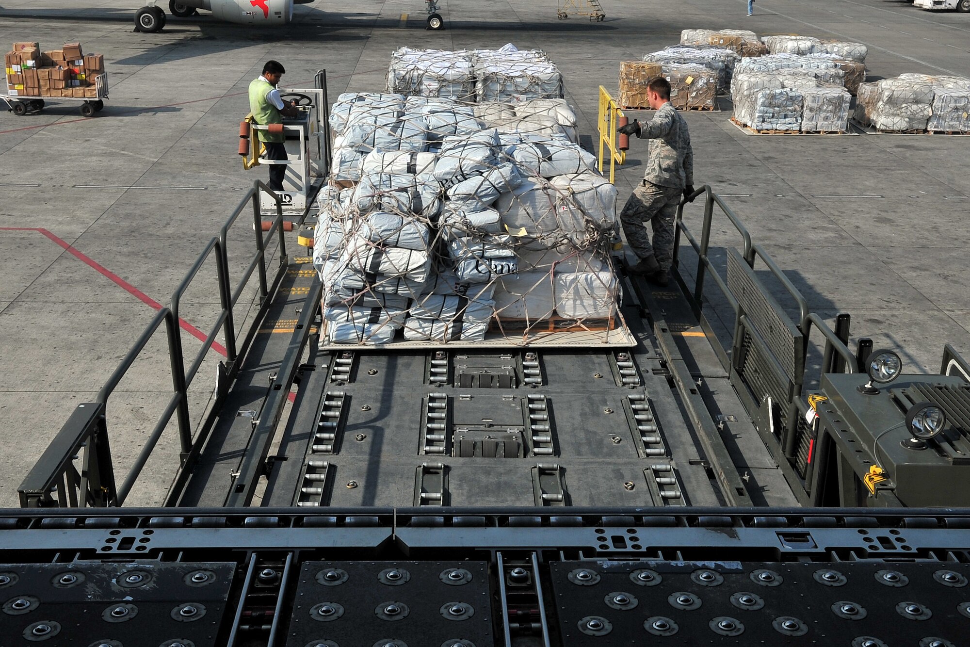 U.S. Air Force Staff Sgt. Josh Foley, 36th Mobility Response Squadron aerial port supervisor, and a Nepalese official help unload relief supplies from an MD-11 cargo aircraft at the Tribhuvan International Airport in Kathmandu, Nepal, May 11, 2015. The Nepalese army and Airmen worked together to process 509,380 pounds of cargo in a 24-hour period from nine aircraft delivering relief supplies after a 7.8 magnitude earthquake struck the nation April 25, 2015. (U.S. Air Force photo by Staff Sgt. Melissa B. White/Released)