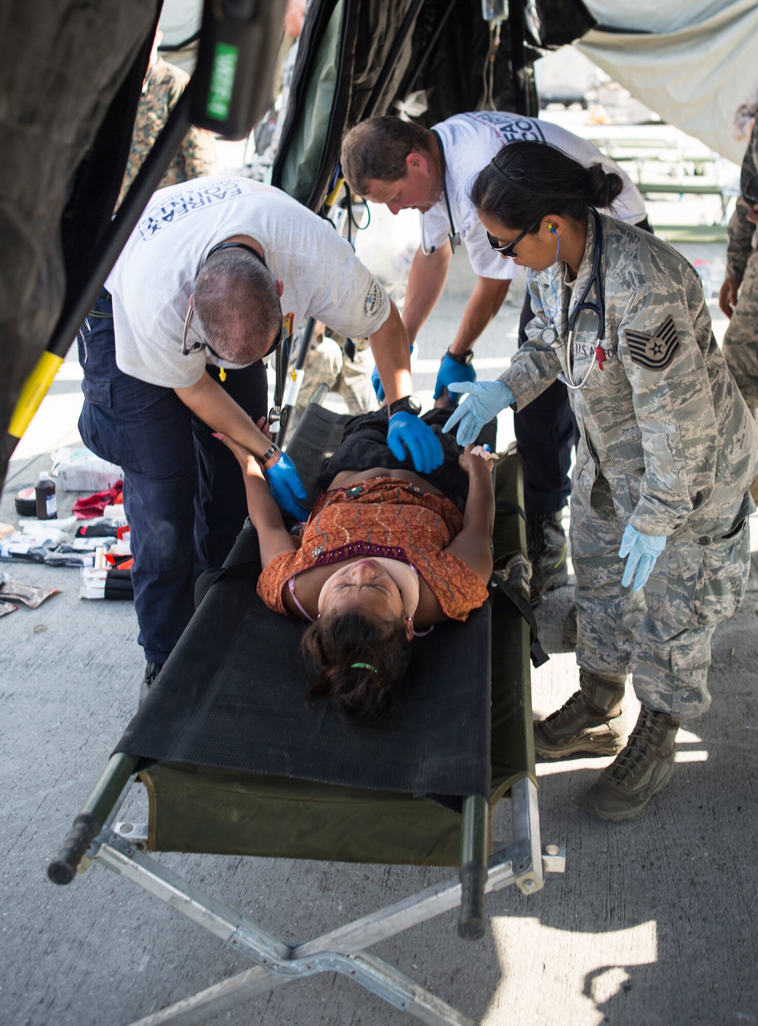 A U.S. Service member with Joint Task Force-505 and rescue and medical personnel provide aid to an earthquake victim at a medical triage area at Tribhuvan International Airport, Kathmandu, Nepal, after a 7.3 magnitude earthquake struck the country, May 12, 2015. JTF-505 along with other multinational forces and humanitarian relief organizations are currently in Nepal providing aid after a 7.8 magnitude earthquake struck the country, April 25, 2015. At Nepal's request the U.S. government ordered JTF-505 to provide unique capabilities to assist Nepal. (U.S. Marine Corps photo by MCIPAC Combat Camera Staff Sgt. Jeffrey D. Anderson/Released)
