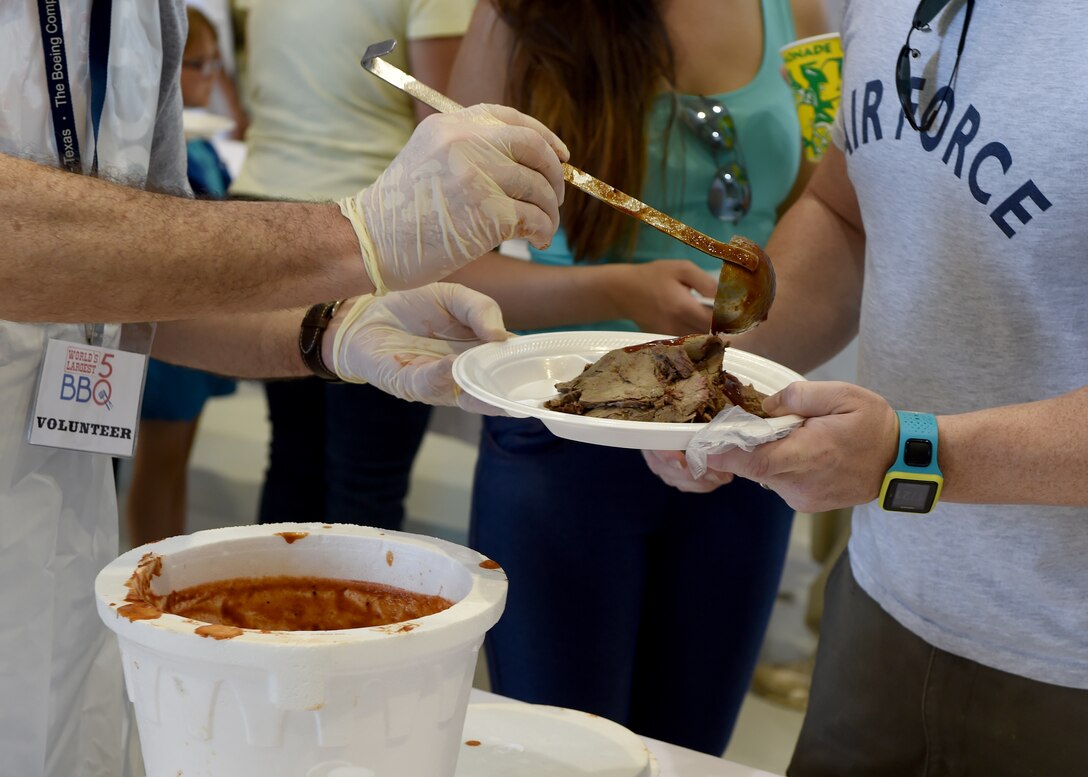 A volunteer pours barbeque sauce for a Dyess Airman during the 2015 World’s Largest Barbeque May 2, 2015, at Dyess Air Force Base, Texas. This year, the Abilene Chamber of Commerce Military Affairs Committee prepared and served more than 4,000 pounds of food to Abilene’s military members and their families. The MAC hosts the barbecue to thank service members of the local community for their daily sacrifice. (U.S. Air Force photo by Airman 1st Class Alexander Guerrero/Released)