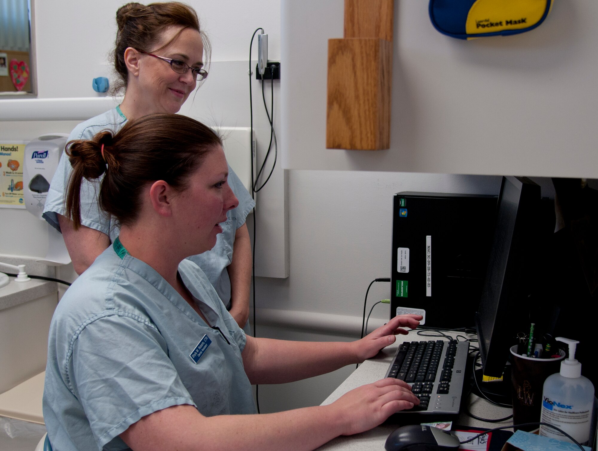 Shyla Roberts, seated, 90th Medical Operations Squadron dental technician, trains Keri Riggs, 90th Medical Group volunteer, on logging dental appointments May 12, 2015, in the medical treatment facility on F.E. Warren Air Force Base, Wyo. Riggs is attending college to be a dental technician. (U.S. Air Force photo by Airman 1st Class Malcolm Mayfield)