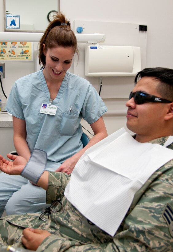 Holli Meno, 90th Medical Group volunteer, checks the blood pressure of Senior Airman Raul Morales, 90th Security Forces Squadron, before he receives his X-ray during his dental appointment May 12, 2015, in the medical treatment facility on F.E. Warren Air Force Base, Wyo. Meno attends Laramie County Community College and is studying to be a dental technician. (U.S. Air Force photo by Airman 1st Class Malcolm Mayfield)