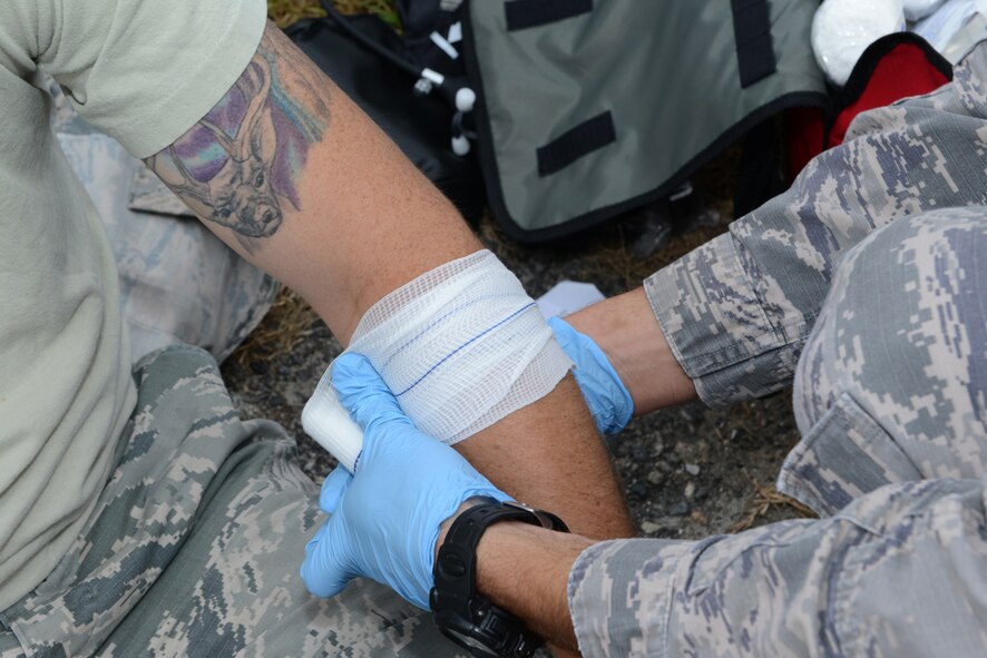 U.S. Air Force Airman 1st Class Brandon Diberardino, 23d Civil Engineer Squadron firefighter, applies a bandage to Staff Sgt. Albert Bullard, 23d CES water fuel system maintenance technician, during the Hurricane Response exercise May 13, 2015, at Moody Air Force Base, Ga. In addition to recovery procedures, the 23d Wing was evaluated on the ability to recover critical assets to include facilities, the runway, electrical power and water in order to return to normal operational status. (U.S. Air Force photo by Airman 1st Class Kathleen D. Bryant/Released)



