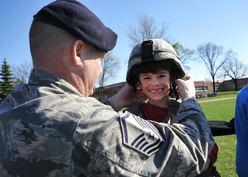 Master Sgt. Kory Henry, 319th Security Forces Squadron first sergeant, fits a Kevlar helmet on a student from the Nathan Twining Elementary and Middle School for Cops for Tots during National Police Week on Grand Forks Air Force Base, N.D., May 12, 2015. The students were able to sit in a Humvee as well as a U.S. Customs and Border Protection patrol vehicle. (U.S. Air Force photo by Airman 1st Class Bonnie Grantham/Released)