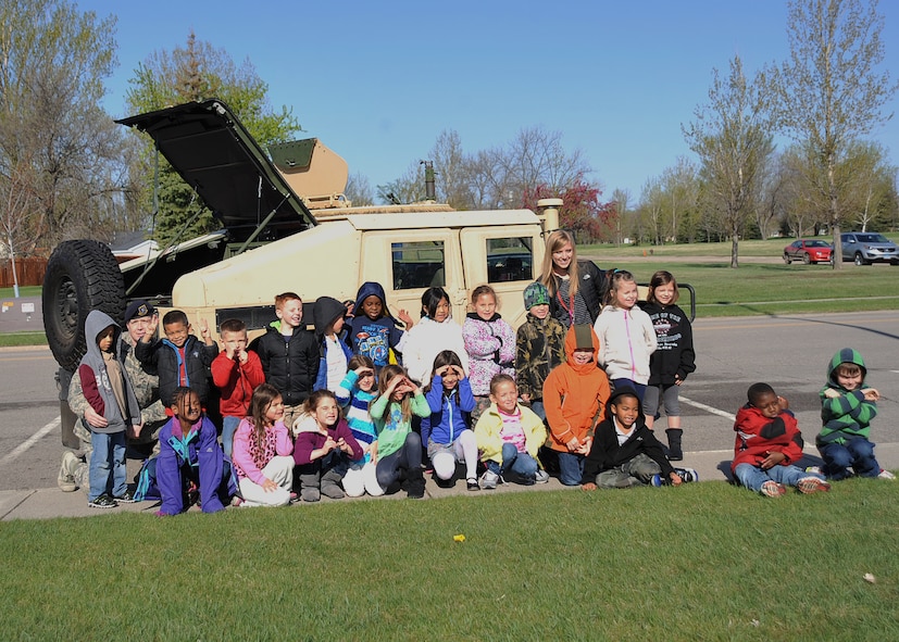 Master Sgt. Kory Henry, 319th Security Forces Squadron first sergeant, poses with students from Nathan Twining Elementary and Middle School in front of a Humvee brought by the 319th Security Forces Squadron for National Police Week on Grand Forks Air Force Base, N.D., May 12, 2015. The students were able to sit in the Humvee and try on a flak vest and Kevlar helmet as well. (U.S. Air Force photo by Airman 1st Class Bonnie Grantham/Released)