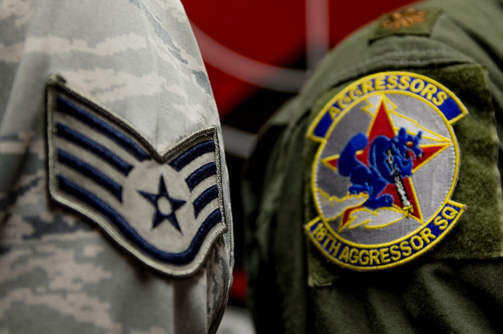 U.S. Air Force Staff Sgt. William Heines, an 18th Aggressor Squadron baron controller, shows his enlisted stripes in relation to a pilot's squadron patch May 12, 2015, at Eielson Air Force Base, Alaska. Both Aggressor pilots and barons spend a large amount of time studying enemy aerial battle tactics from around the world and teach others how combat these threats. (U.S. Air Force photo by Staff Sgt. Shawn Nickel/Released)
