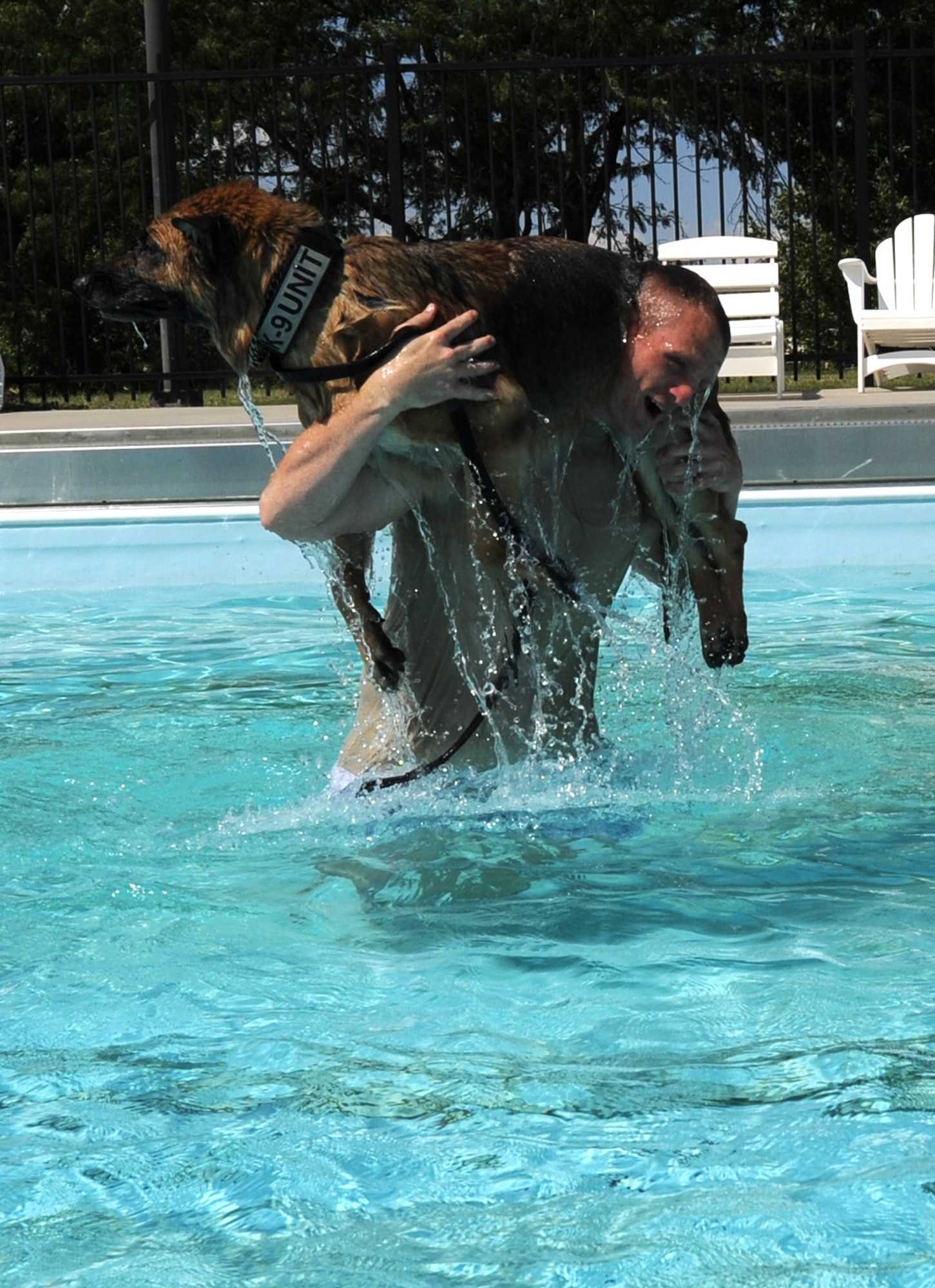 A 22nd Security Forces Squadron Airman carries 22nd SFS Military Working Dog Rakker across the base pool during aggression training Sept. 10, 2013, at McConnell Air Force Base, Kan. Rakker, after 49 dog years of service was formally retired May 13, 2015. (U.S. Air Force photo by Senior Airman Laura L. Valentine)