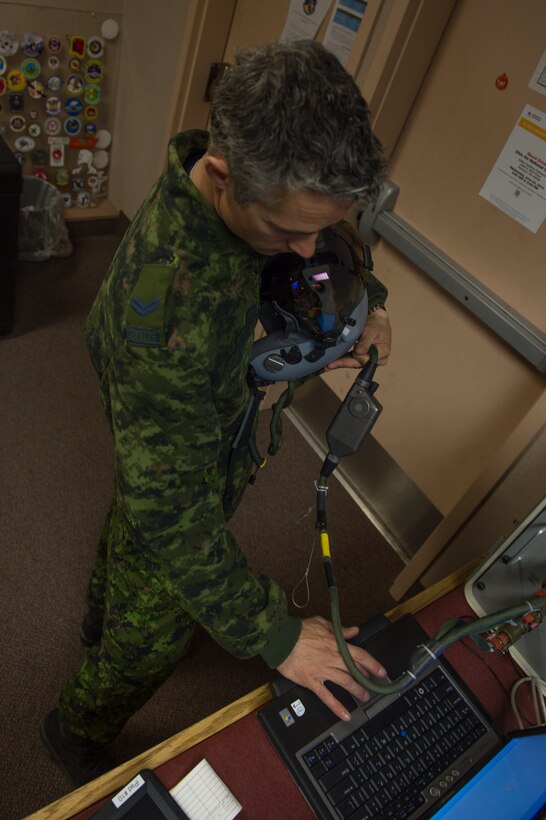 Royal Canadian air force Cpl. Yannick Deschesnes, an aircrew flight equipment technician from the 425th Tactical Fighter Squadron, tests a joint helmet-mounted cueing system for a CF-18 Hornet pilot at Eielson Air Force Base, Alaska, May 7, 2015, during RED FLAG-Alaska (RF-A) 15-2. After testing and certifying aircrew flight equipment, Deschesnes will transition to the role of crew chief and launch jets during RF-A to reduce the amount of manning required while on temporary duty. (U.S. Air Force photo by Staff Sgt. Shawn Nickel/Released)