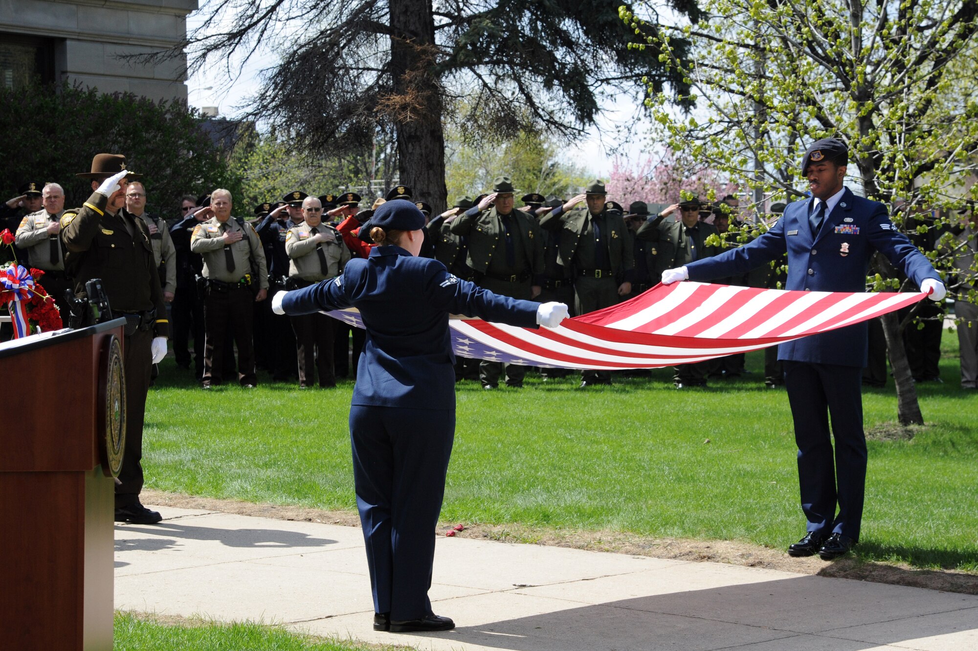 Airman 1st Class Ashley Miller and Senior Airman Eric Bailey from the 319th Security Forces Squadron perform a flag folding presentation during the annual Police Week memorial ceremony in Grand Forks, N.D., May 12, 2015. The ceremony paid tribute to law enforcement officers who lost their lives in the line of duty. (U.S. Air Force photo by Staff Sgt. David Dobrydney/released)