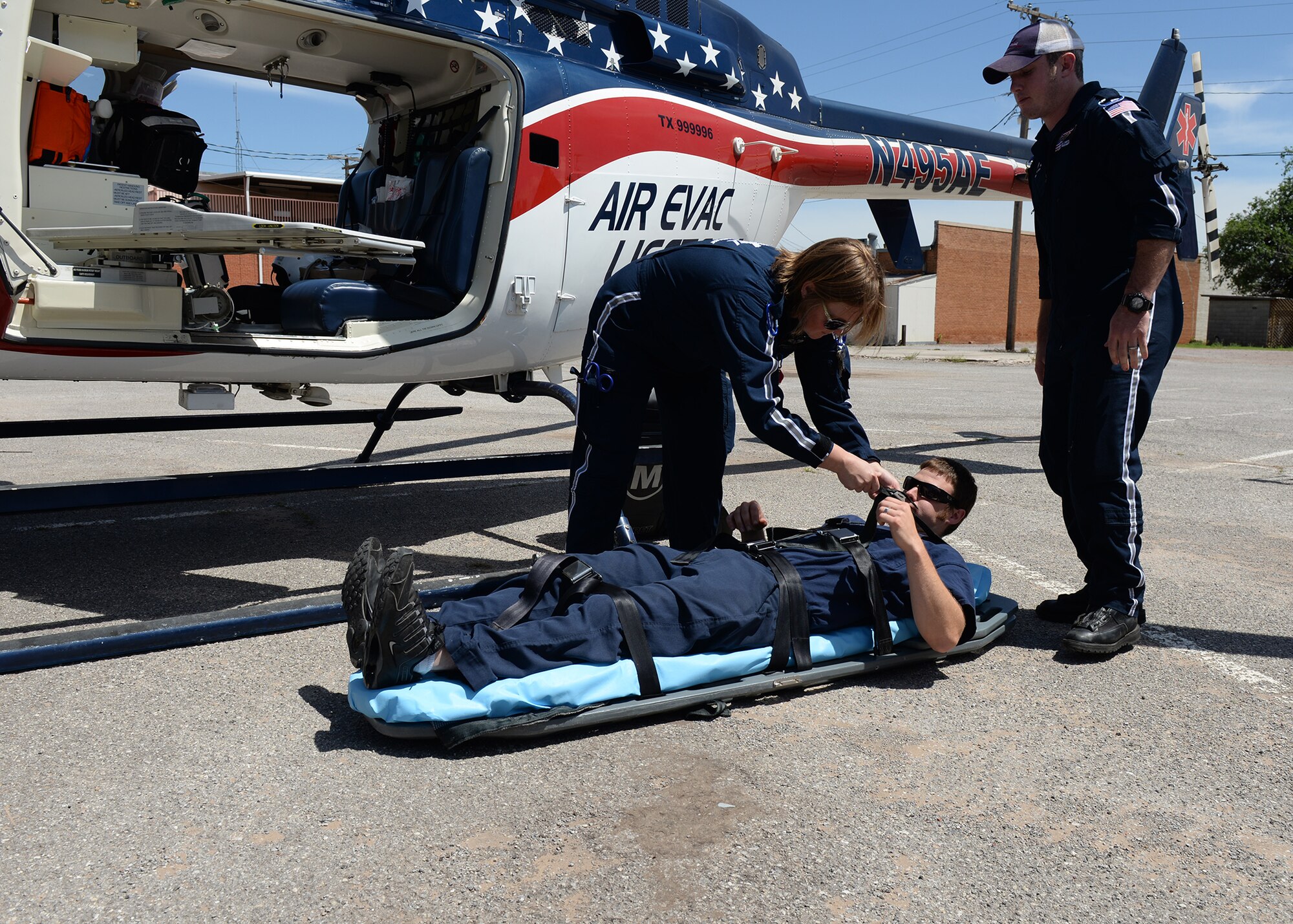 ALTUS AIR FORCE BASE, Okla. – Amanda Holt, Air Evac Lifeteam flight nurse, and Dallas Smith, paramedic for the Air Evac Lifeteam, strap Altus Fire Department firefighter Johnathan Hazlewood to a litter during a demonstration of procedures to load patients into the evacuation helicopter at the Altus Fire Department May 11, 2015. The Air Evac Lifeteam spoke with members of the Altus police and fire departments and the Altus AFB fire department about how the air evacuation team works. (U.S. Air Force photo by Senior Airman J. Zuriel Lee/Released)