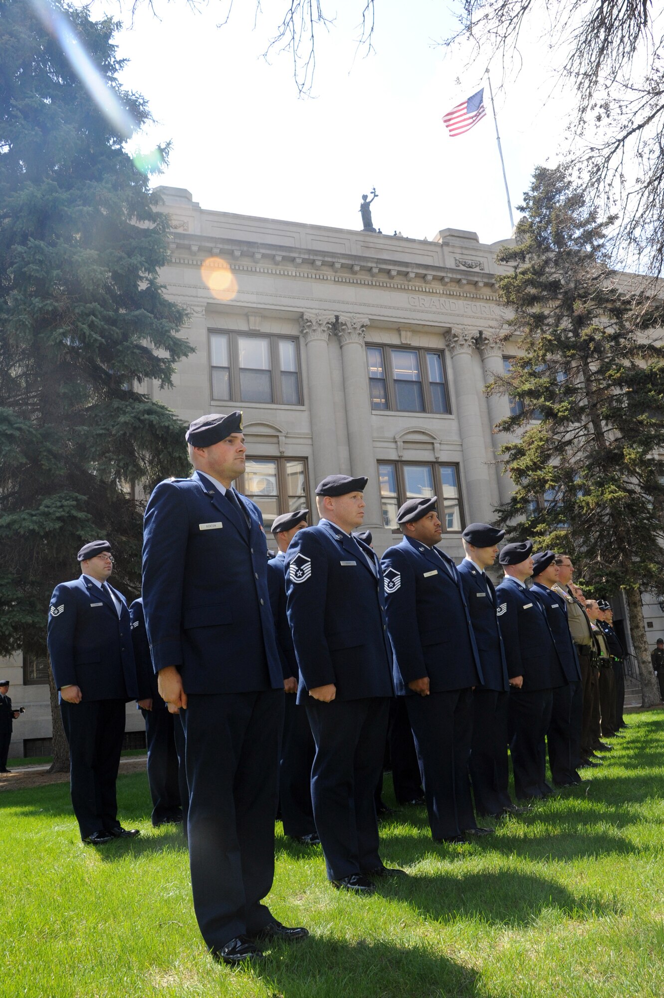 A detachment from the 319th Security Forces Squadron from Grand Forks Air Force Base stands at attention outside the Grand Forks County Courthouse in Grand Forks, N.D., May 12, 2015. The Airmen were present for the annual Police Week memorial ceremony which brought together officers from 18 different law enforcement agencies. (U.S. Air Force photo by Staff Sgt. David Dobrydney/released)