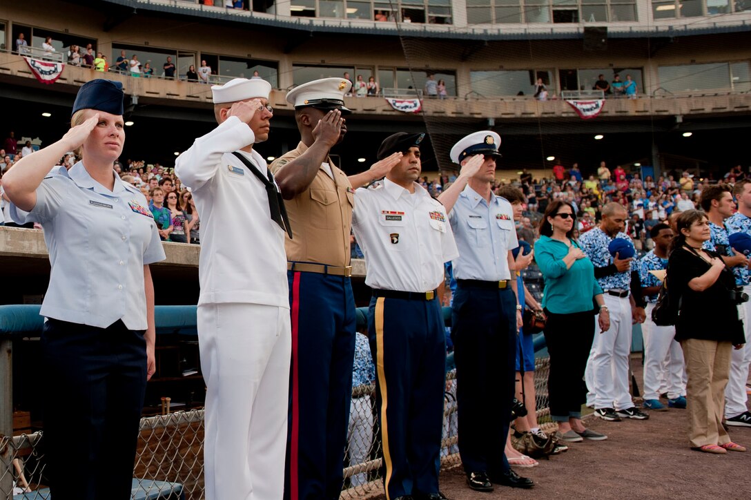 U.S. Service members salute during the playing of the National Anthem at the Norfolk Tides Armed Forces Appreciation night in Norfolk, Va., May 9, 2015. Each member was selected to represent their service by throwing the first pitch of the game, the Norfolk Tides against the Buffalo Bisons.  (U.S. Air Force photo by Staff Sgt. Stephanie Rubi/Released)