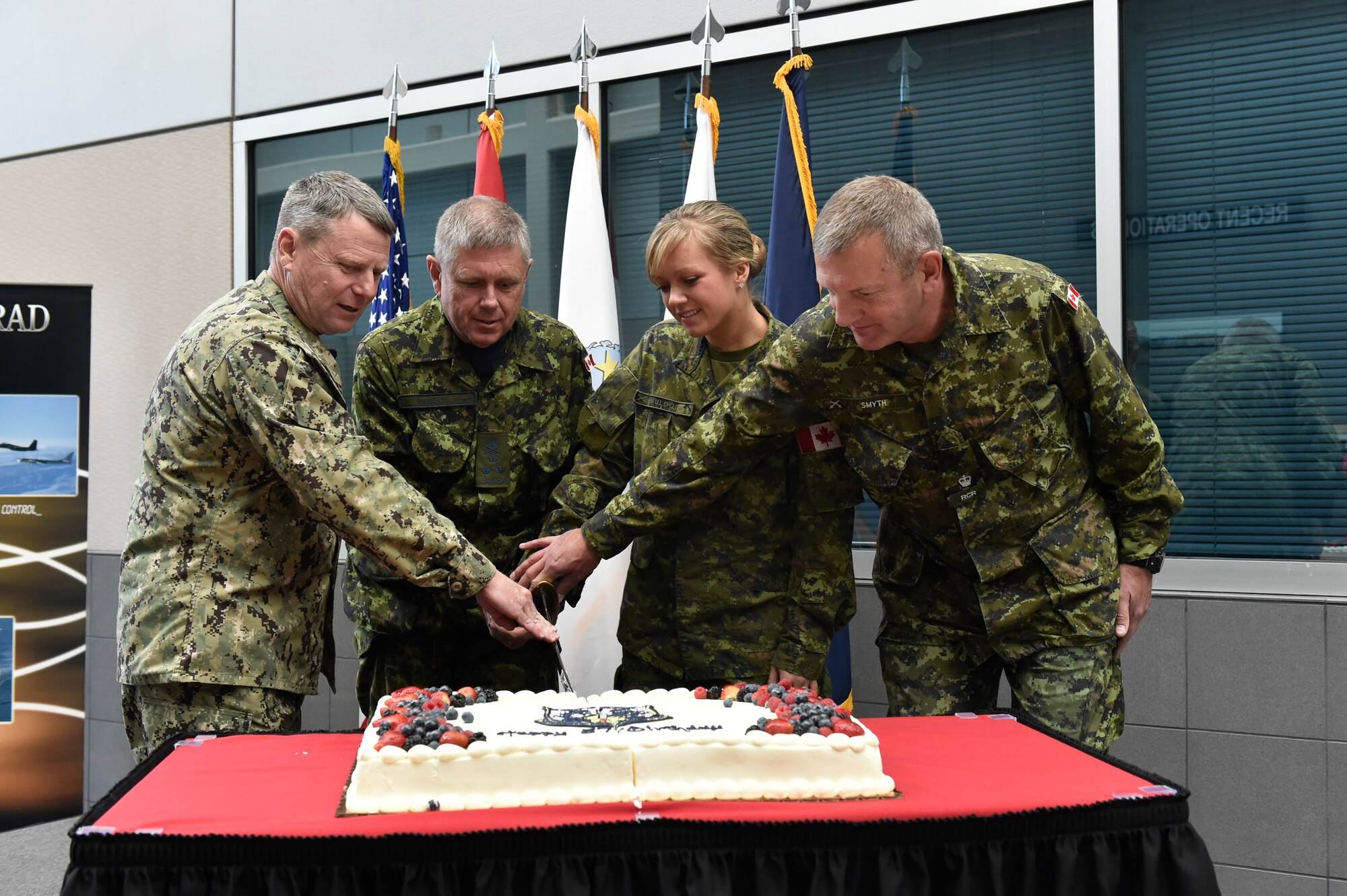 PETERSON AIR FORCE BASE, Colorado -- Adm. Bill Gortney, commander of the North American Aerospace Defense Command and U.S. Northern Command, cuts a cake with Canadian forces members (left to right) Lt. Gen. Alain Parent, NORAD deputy commander, Cpl. Brandi Muldoon and Maj. Randall Smyth, during NORAD's 57th birthday celebration here May 12. The tradition of celebrating NORAD's anniversary dates back to the original signing of the NORAD agreement May 12, 1958. The command traditionally celebrates with a cutting by the most senior and junior members.  (U.S. Air Force photo by Master Sgt. Andy Bellamy)