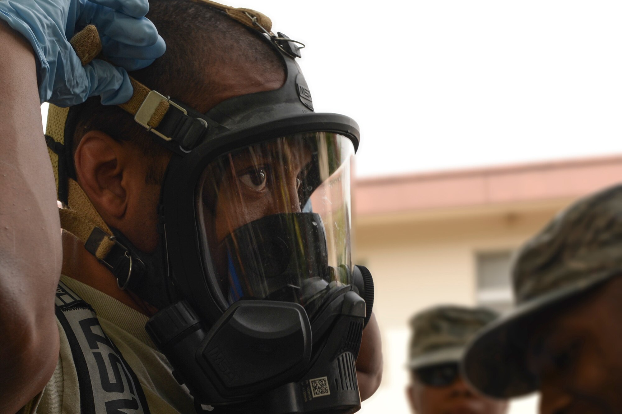 Staff Sgt. Sheraz Cedeno, 374th Civil Engineer Squadron NCO in charge of emergency management and operations, tightens his chemical mask before entering the scene of a mock environmental hazard, May 6, 2015, at Yokota Air Base, Japan.  Participants practiced responding to a training scenario involving a passed out resident inside base housing. (U.S. Air Force photo by Airman 1st Class Elizabeth Baker/Released)