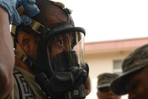 Staff Sgt. Sheraz Cedeno, 374th Civil Engineer Squadron NCO in charge of emergency management and operations, tightens his chemical mask before entering the scene of a mock environmental hazard, May 6, 2015, at Yokota Air Base, Japan.  Participants practiced responding to a training scenario involving a passed out resident inside base housing. (U.S. Air Force photo by Airman 1st Class Elizabeth Baker/Released)