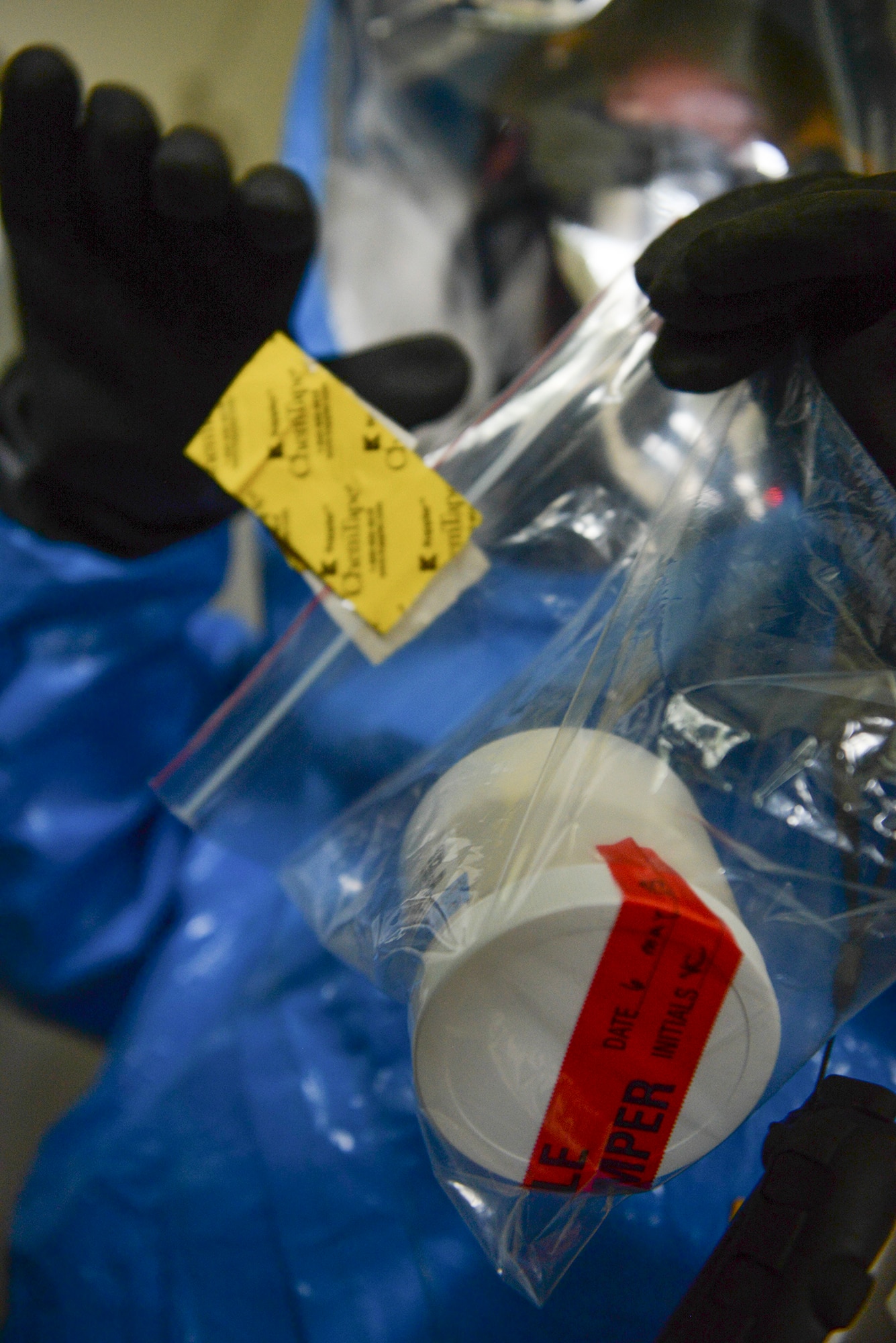 An Airman from the 374th Civil Engineer Squadron seals a sample found at the scene of a mock environmental hazard, May 6, 2015, at Yokota Air Base, Japan.  Responders had to conduct all investigations under the constraint of limited oxygen reserves, the heat of the protective suit and the challenge of thick rubber gloves. (U.S. Air Force photo by Airman 1st Class Elizabeth Baker/Released)