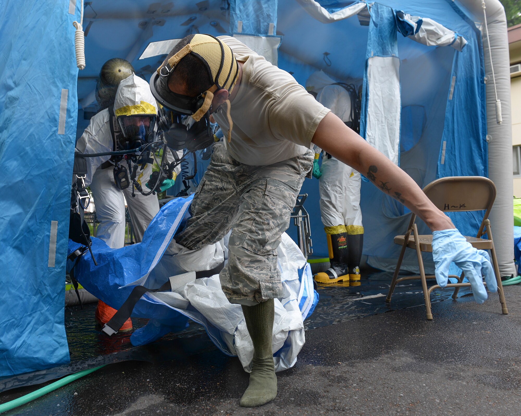 Staff Sgt. Sheraz Cedeno, 374th Civil Engineer Squadron NCO in charge of emergency management and operations, steps out of a protective suit after completing a mock chemical threat training scenario, May 6, 2015, at Yokota Air Base, Japan.  Cedeno was part of a three-man team, which investigated a simulated environmental hazard scenario inside base housing. (U.S. Air Force photo by Airman 1st Class Elizabeth Baker/Released)