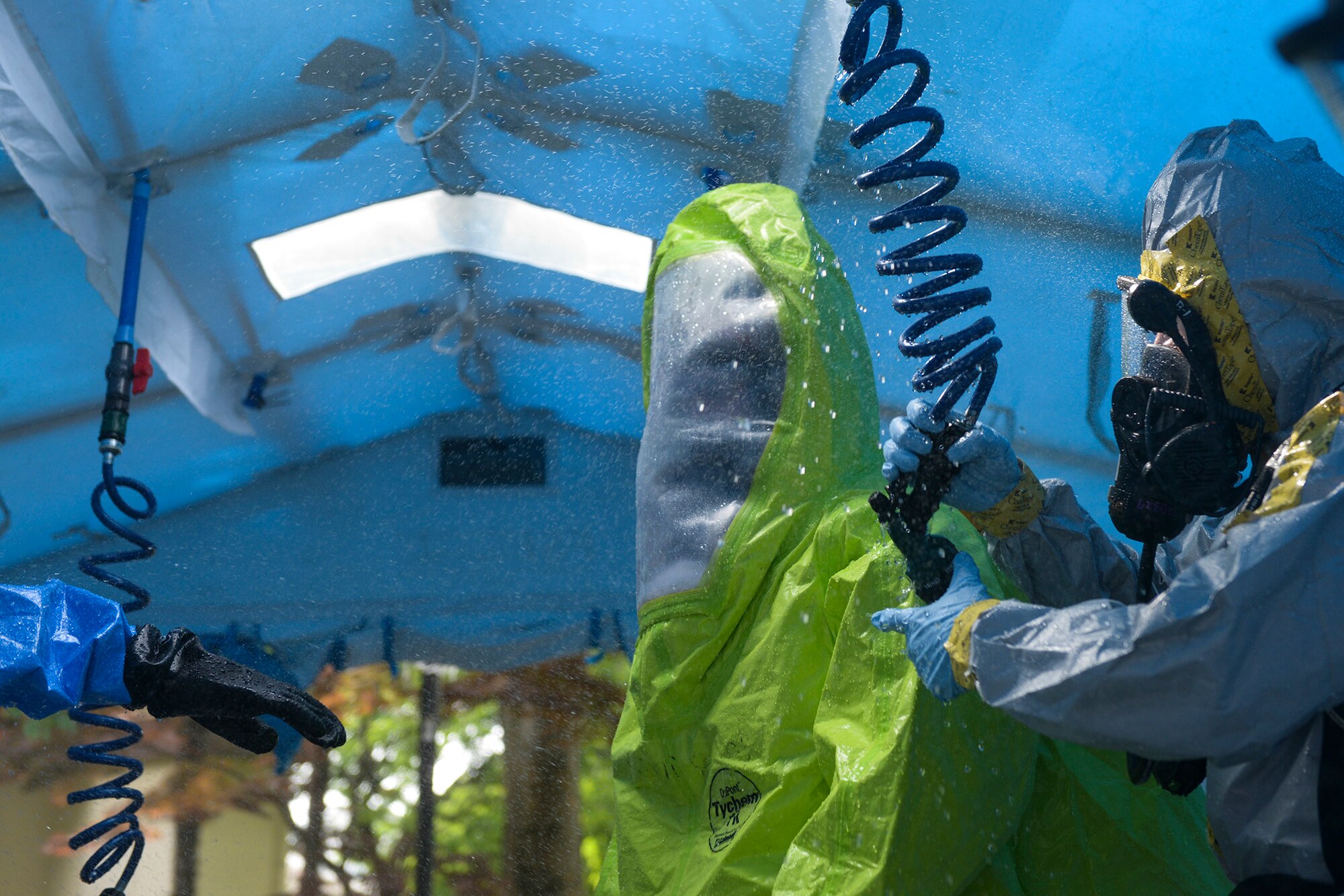 Senior Airman Craig Deacon, left, 374th Civil Engineer Squadron driver operator, passes through a decontamination shower tent, May 6, 2015, at Yokota Air Base, Japan. Emergency responders passed through the tent after coming into contact with simulated hazardous materials. (U.S. Air Force photo by Airman 1st Class Elizabeth Baker/Released)